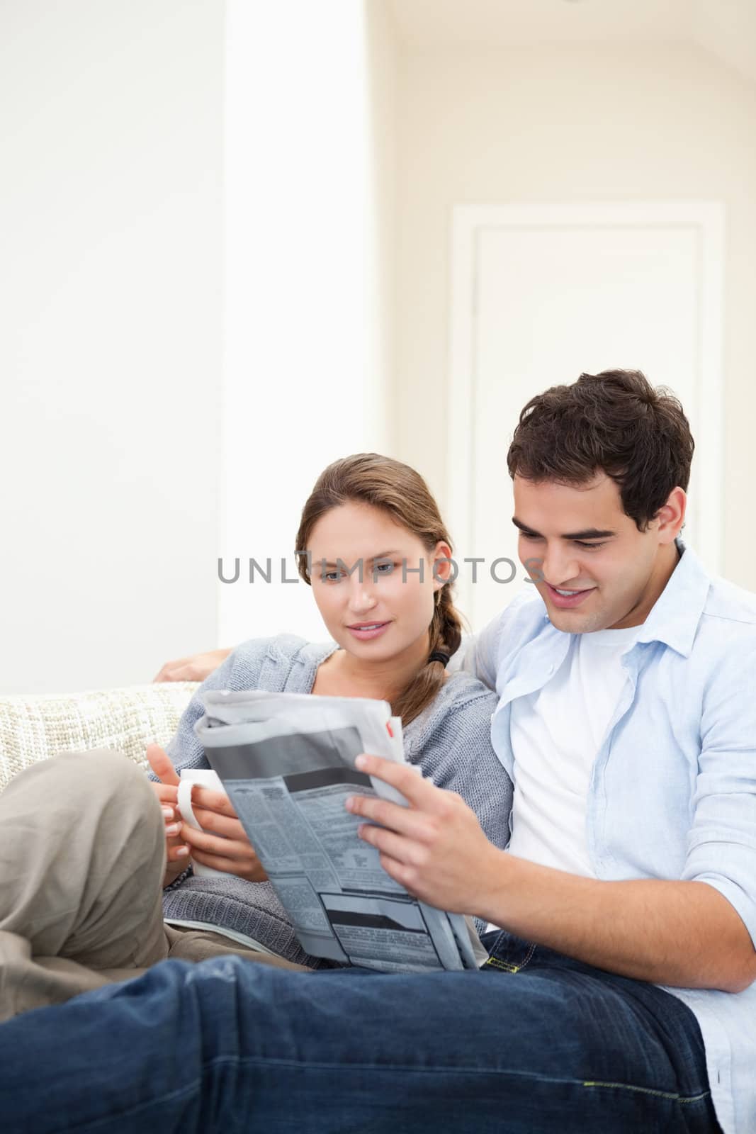 Young Couple embracing while reading a newspaper in a sitting room