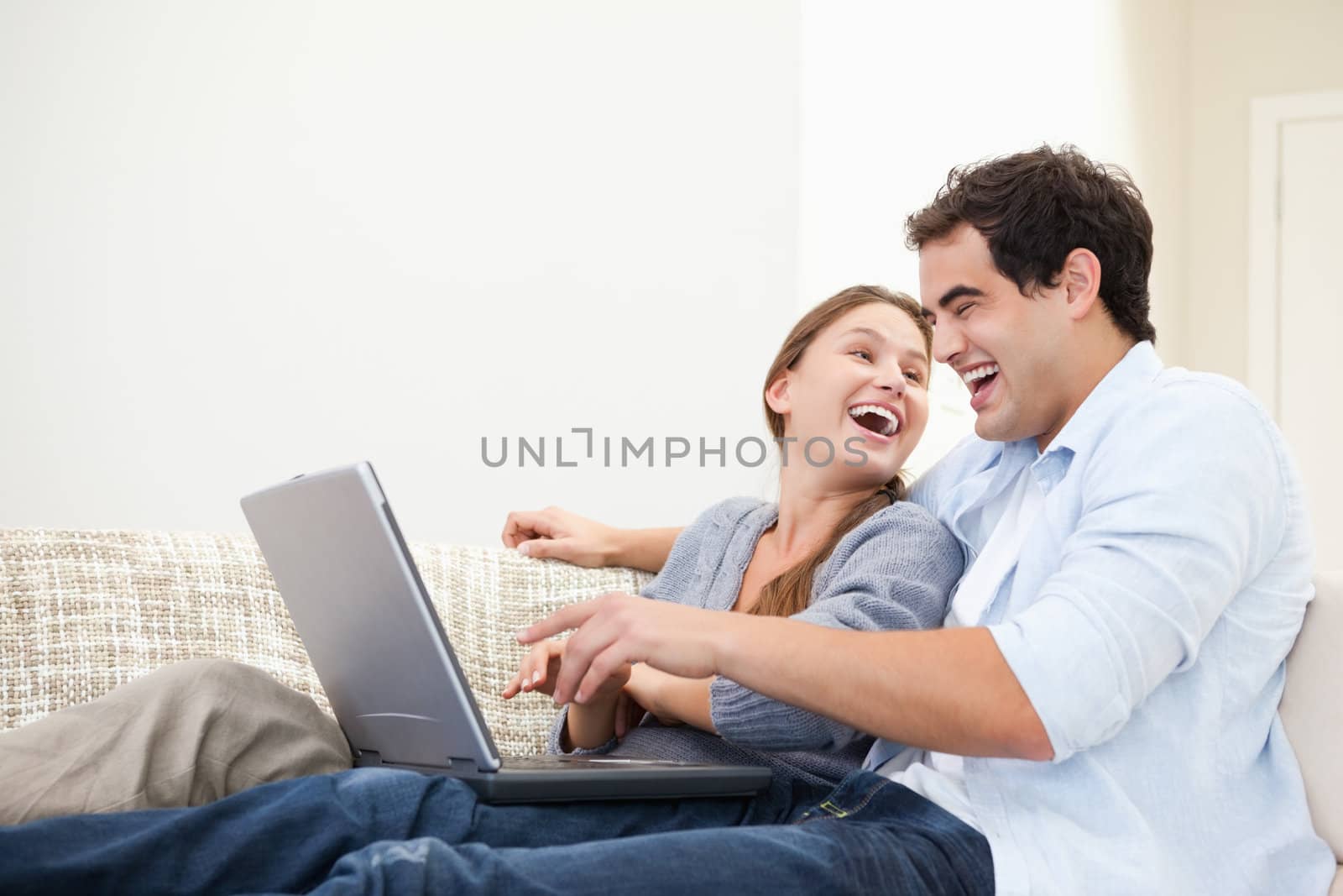 Couple laughing while typing on a computer indoors