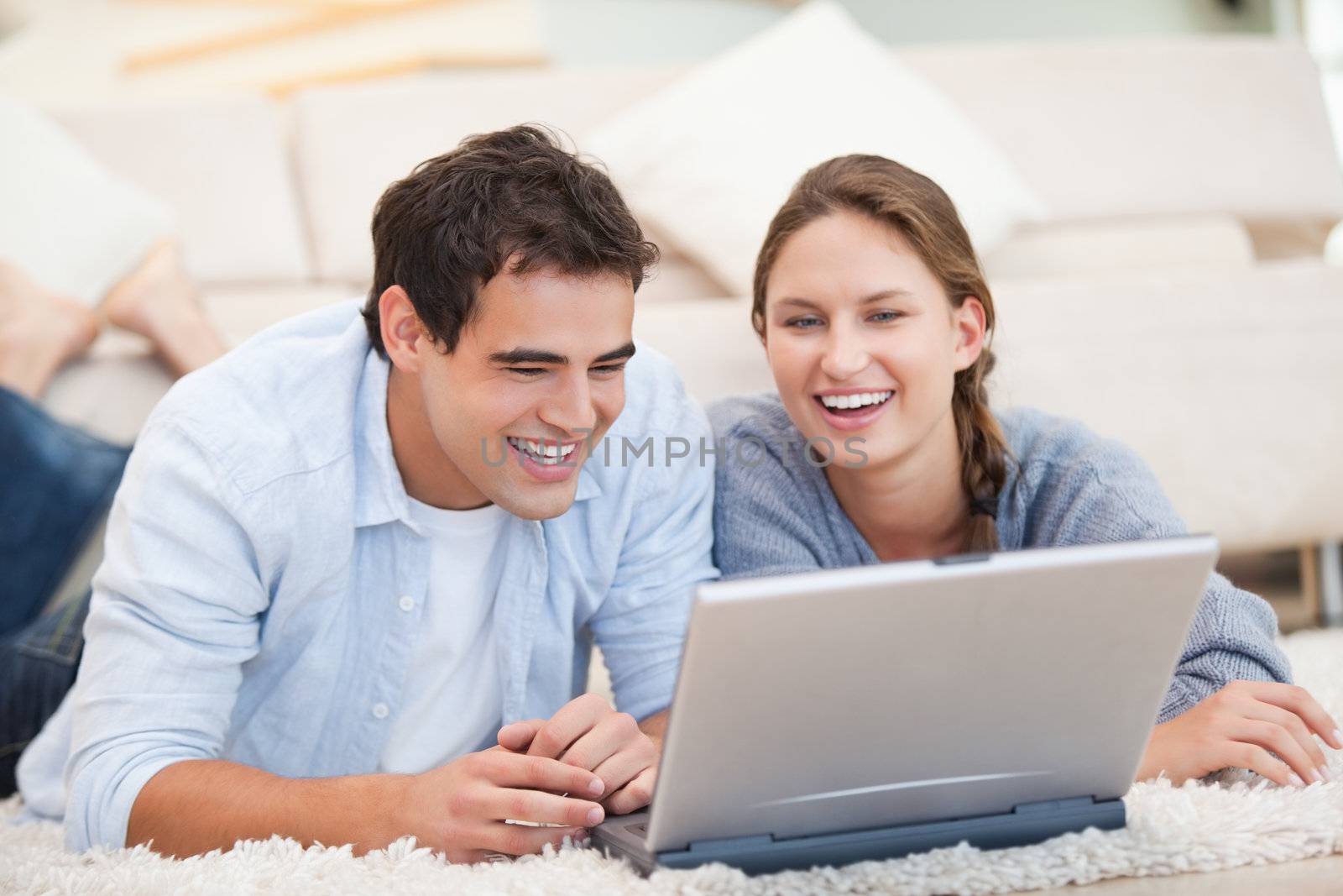 Young Couple lying while using a computer by Wavebreakmedia
