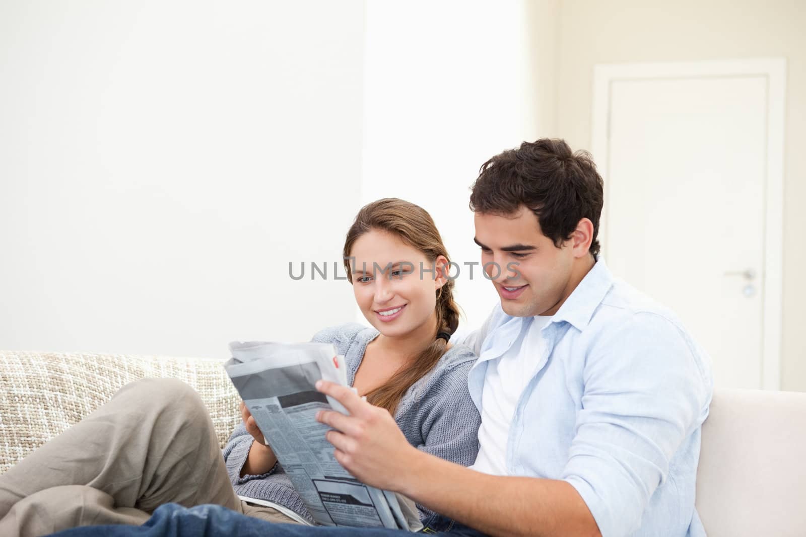 Couple lying while reading a newspaper in a sitting room