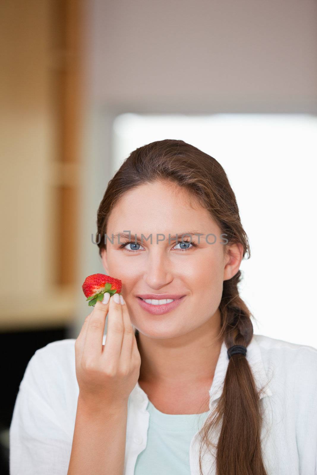 Woman eating a strawberry  by Wavebreakmedia