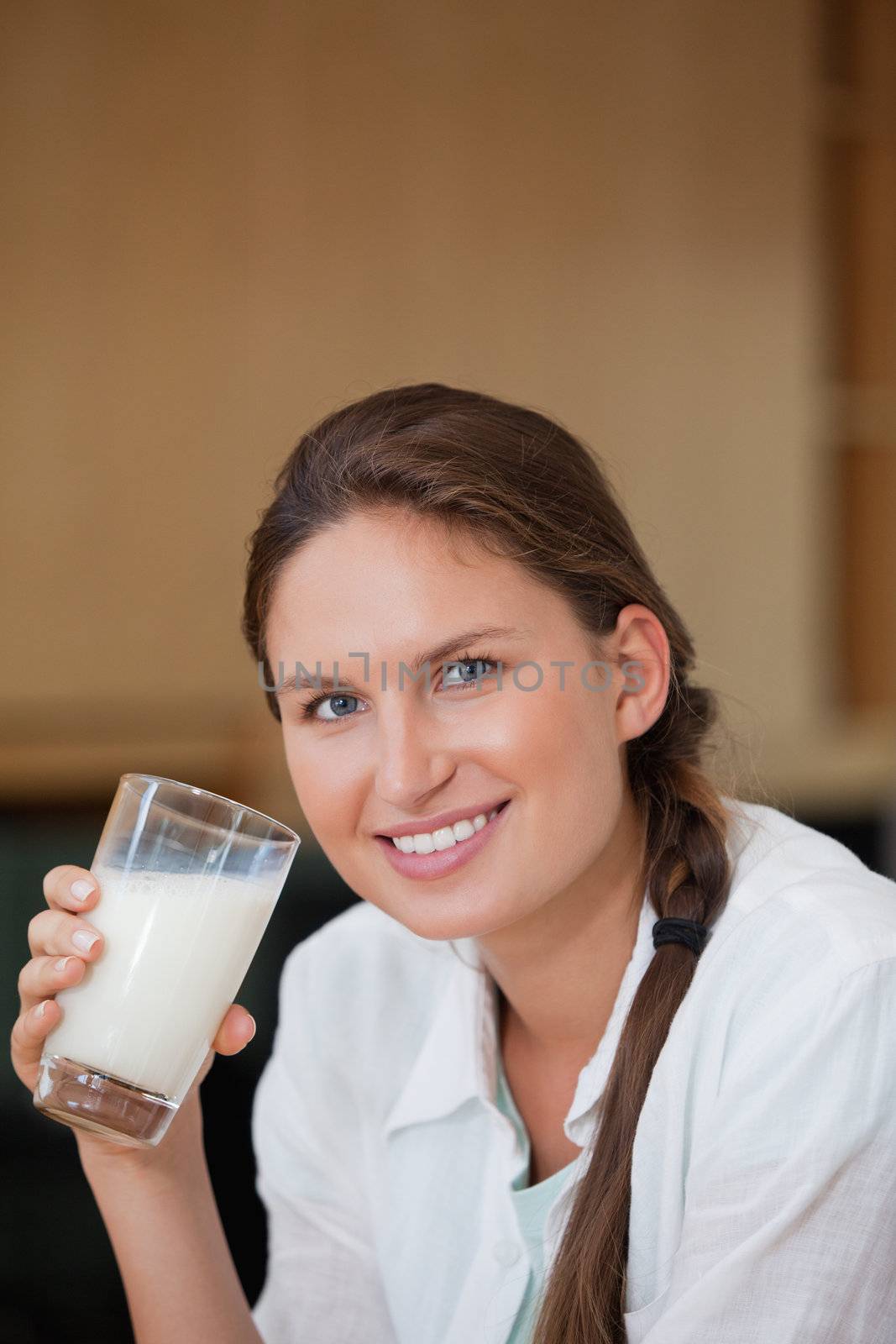 Woman holding a glass of milk while smiling in a kitchen