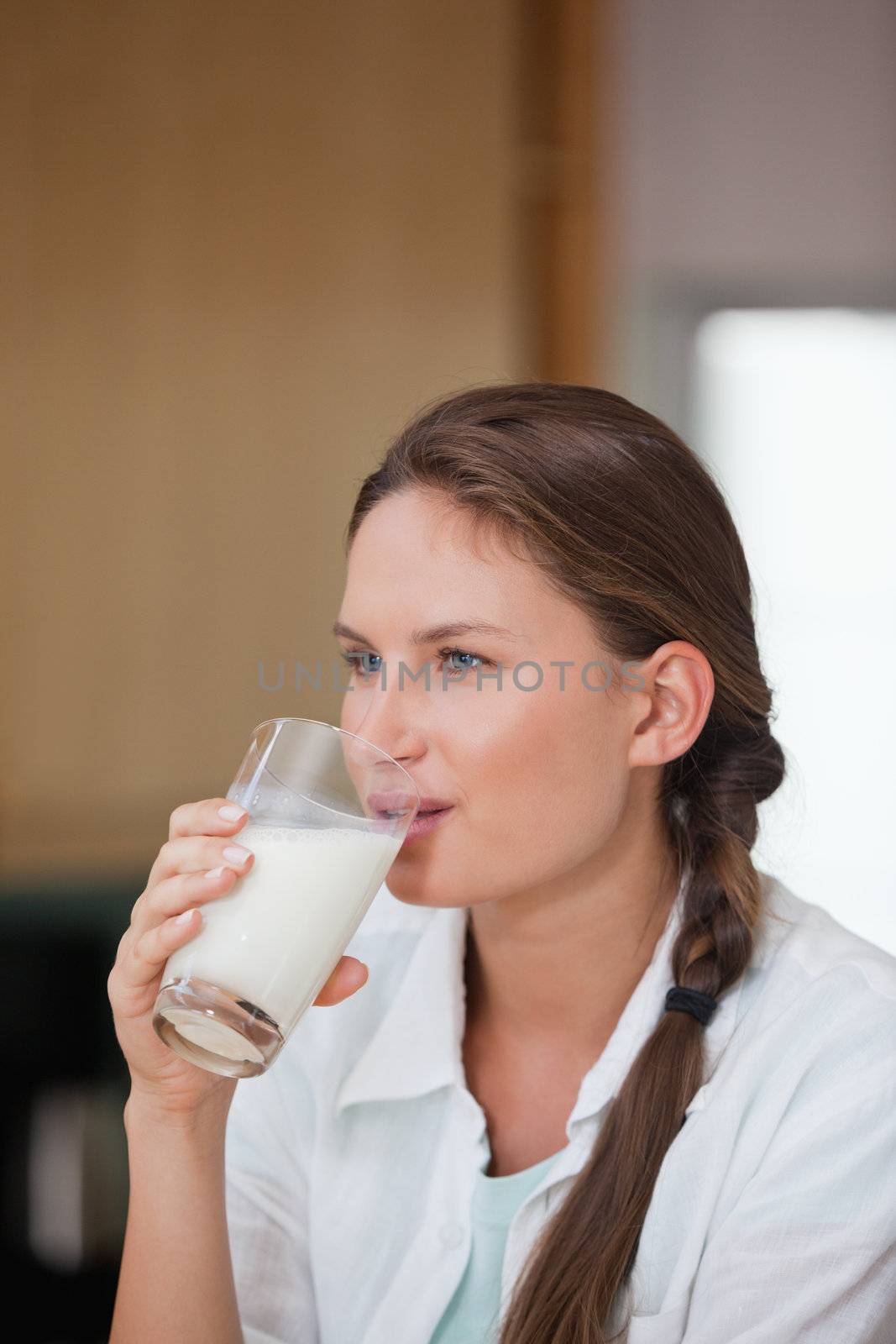 Woman drinking a glass of milk while looking away in a kitchen