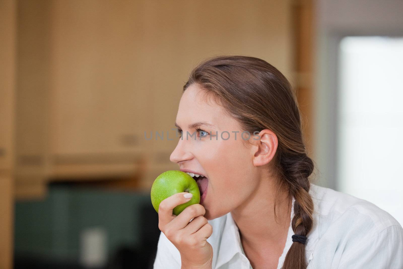 Woman eating an apple in a kitchen 