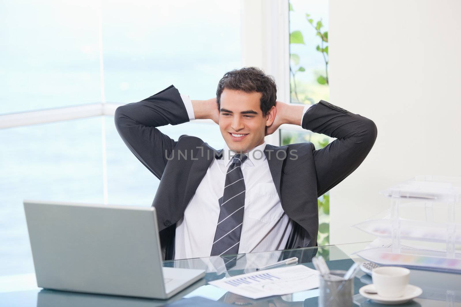 Man crossing his arms behind his head  in an office