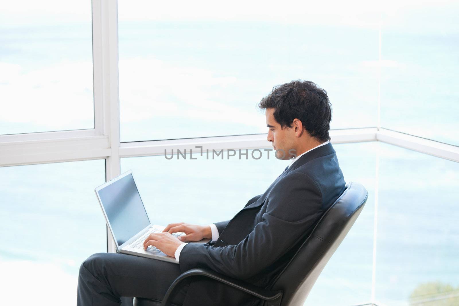 Man sitting on a chair while typing on a computer  by Wavebreakmedia