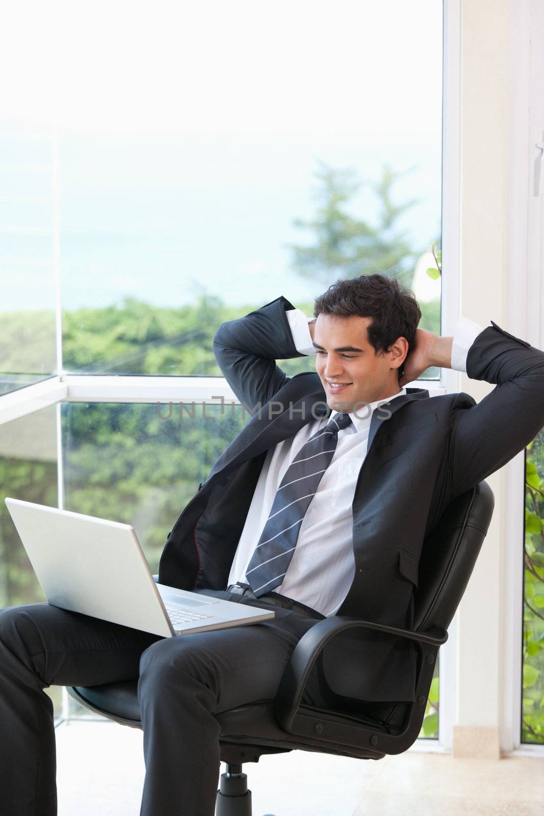 Men sitting in a chair looking at a laptop in an office