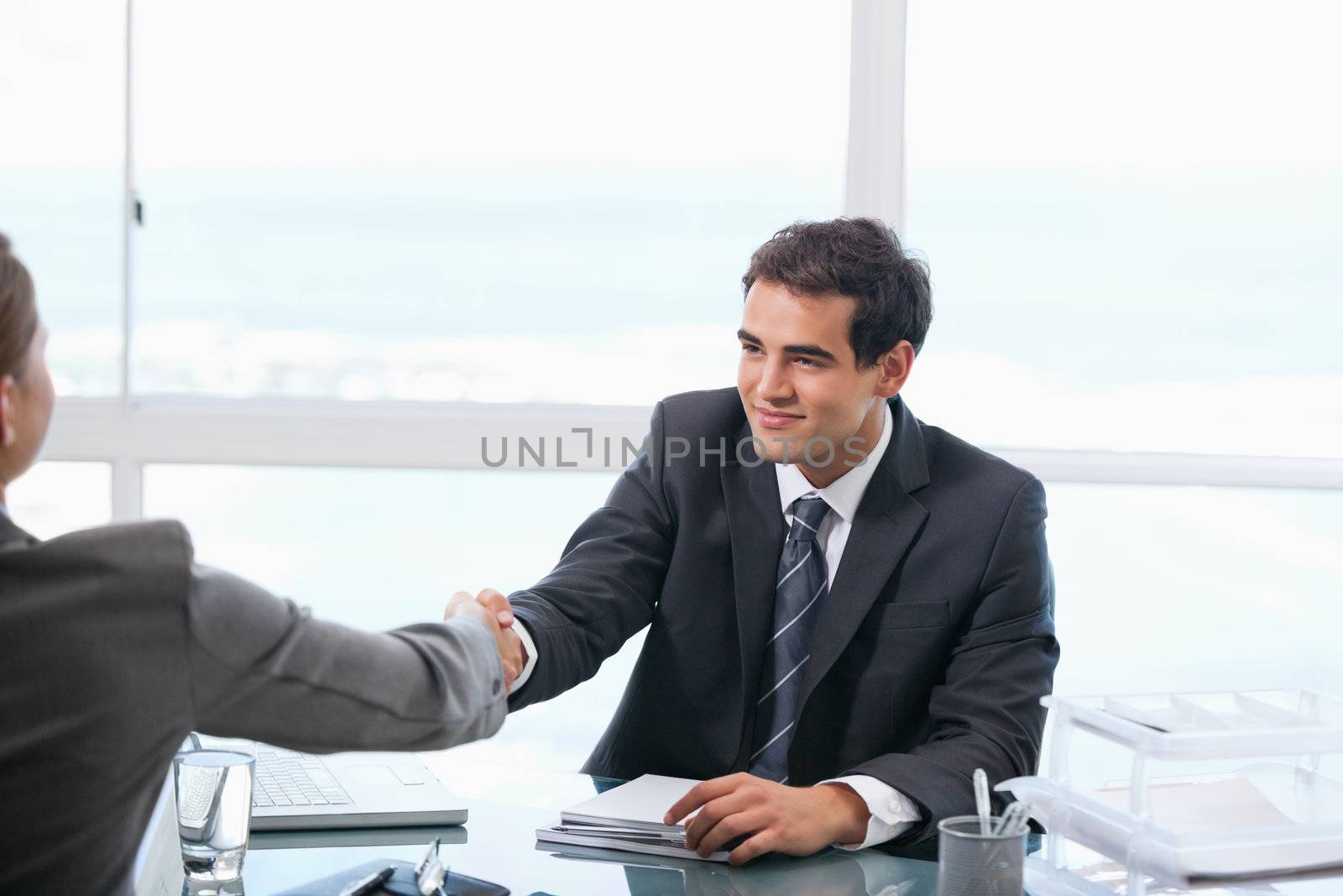 Businessman shaking hands with a client while sitting by Wavebreakmedia