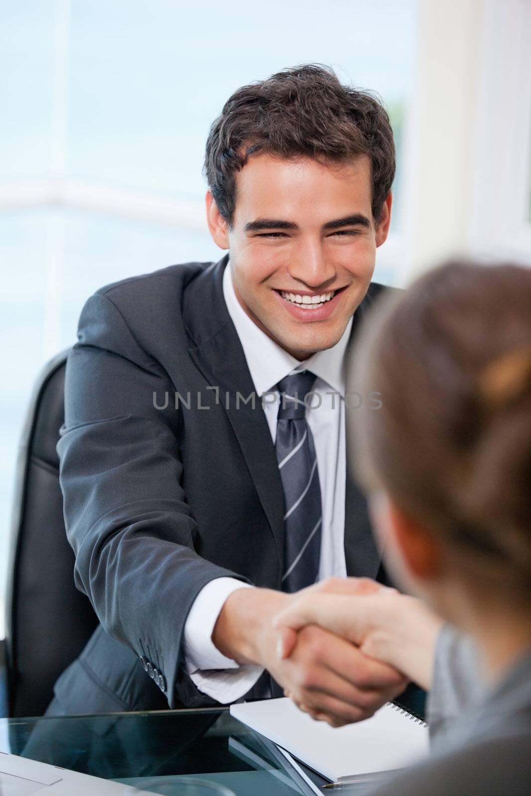 Businessman shaking hands with a client while smiling in an office