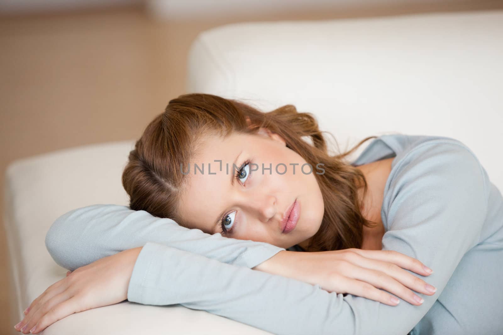 Woman crossing harms while lying on a sofa looking up by Wavebreakmedia