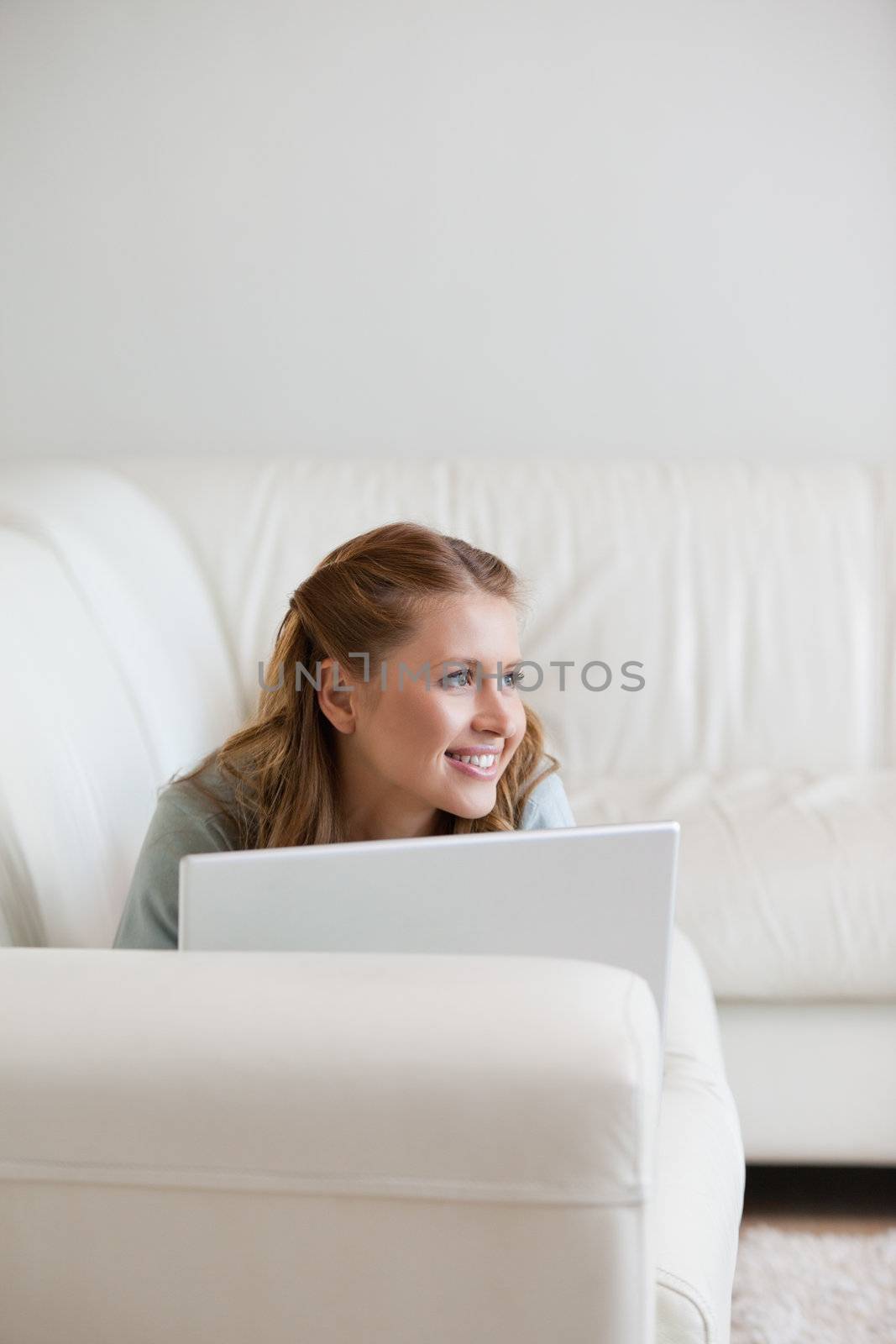 Woman looking away lying on a sofa against grey background