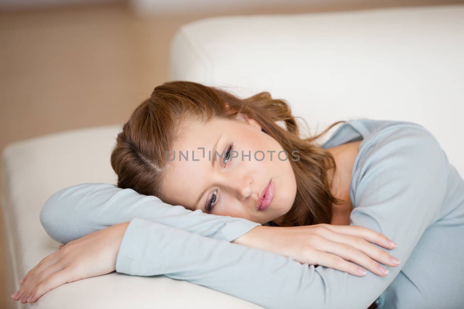Woman lying on a sofa crossing her arms indoors