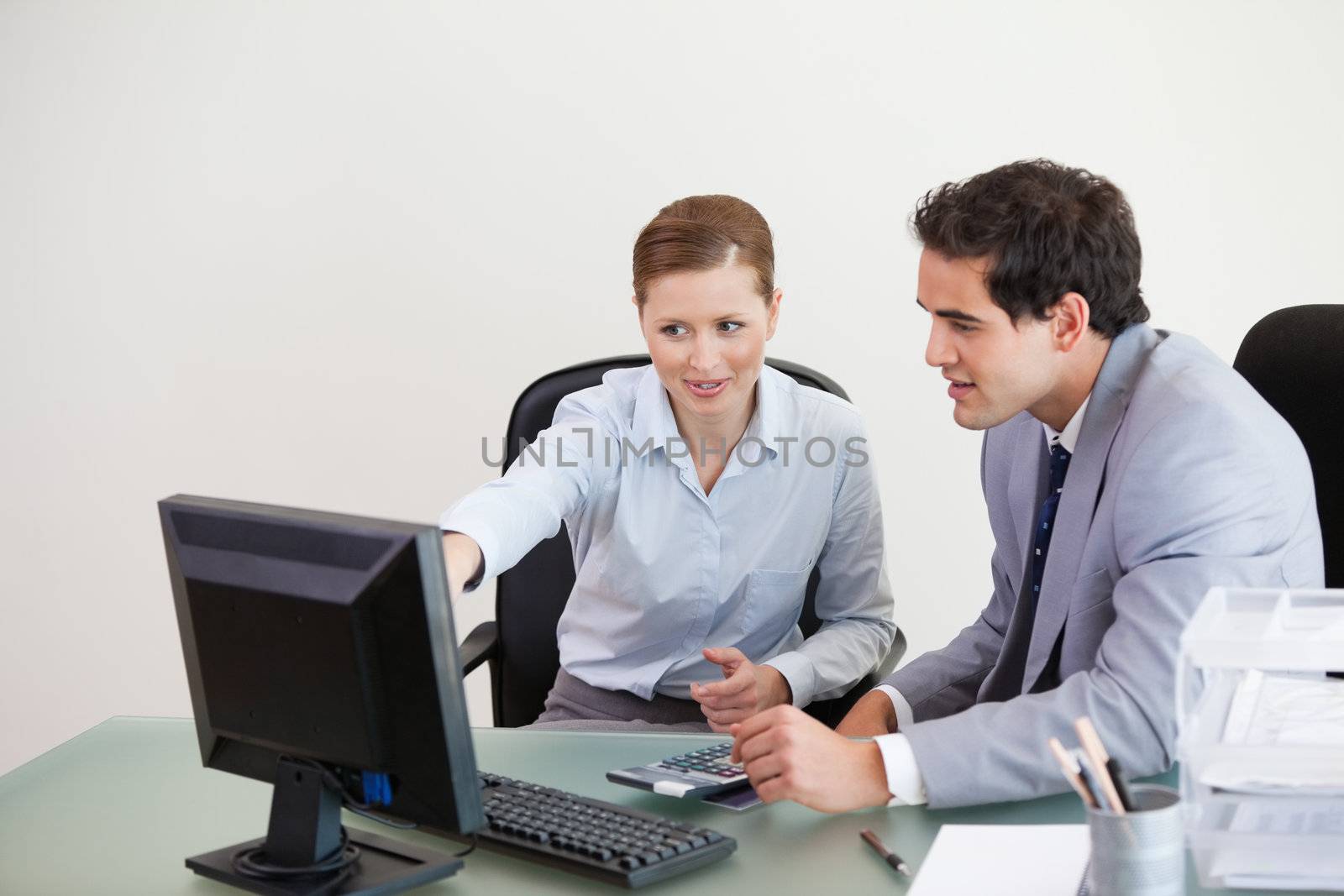 Colleagues working together on a computer against grey background