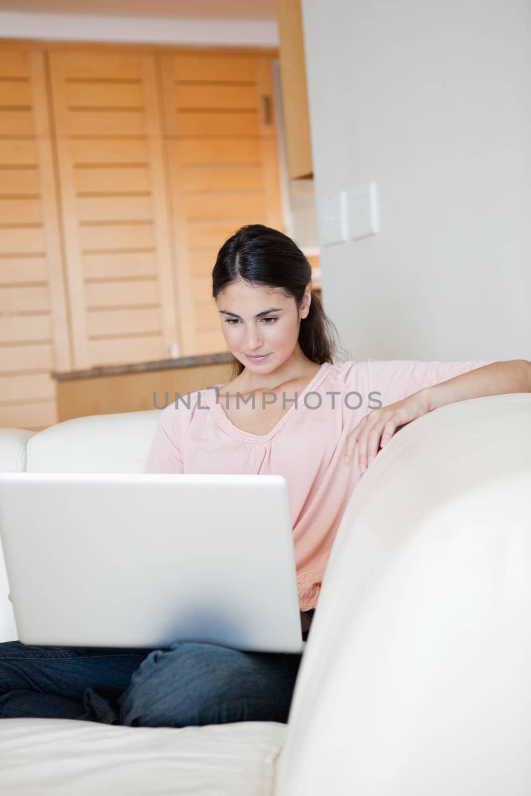 Woman using a laptop while sitting on a sofa by Wavebreakmedia
