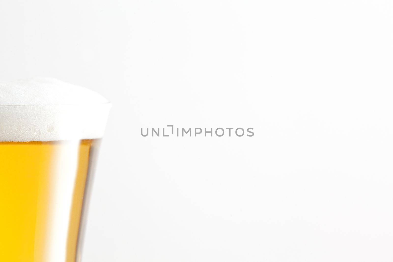 Glass of beer and foam against a white background by Wavebreakmedia