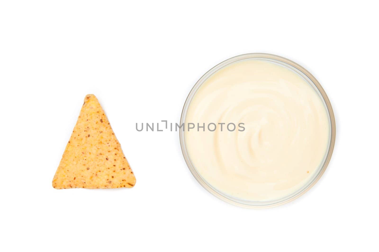 A bowl of dip and a nacho placed side by side by Wavebreakmedia
