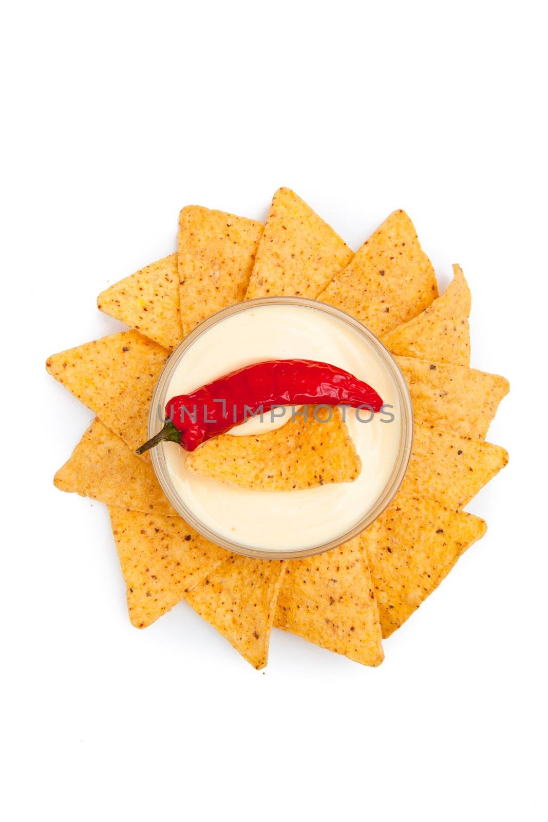 Pepper and nacho dipped into a bowl of white dip surrounded by white dip