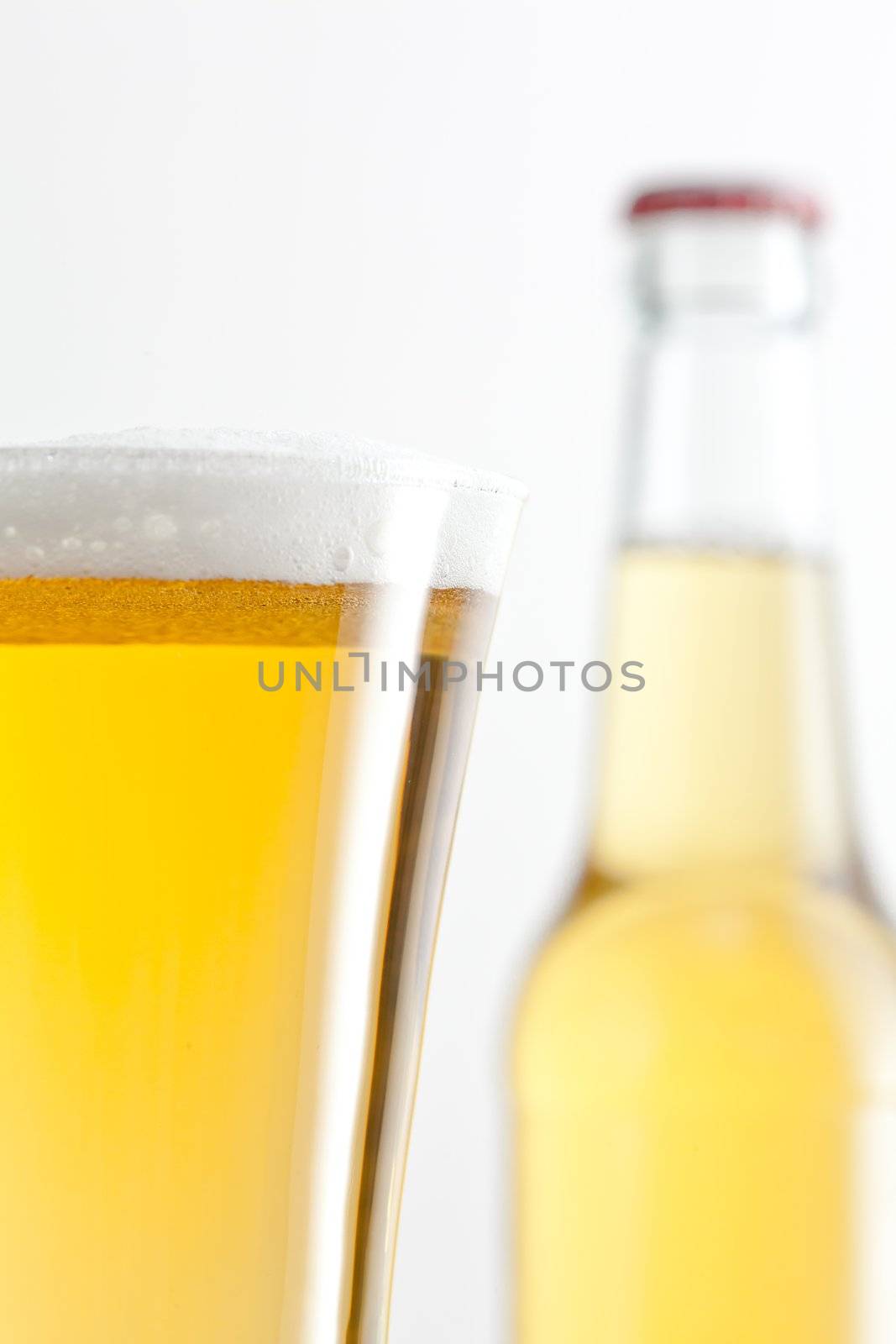 Glass and bottle full of beer against a white background