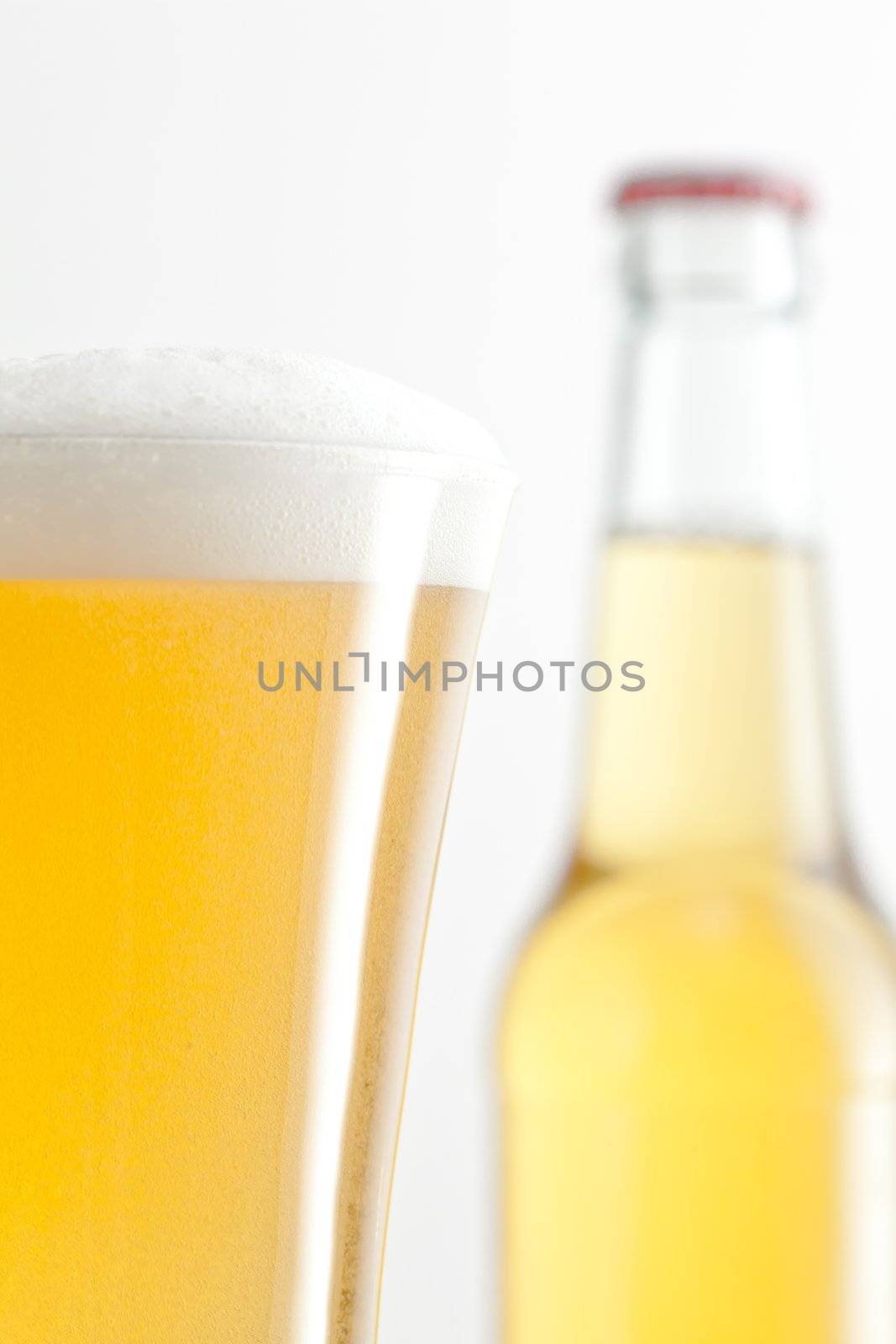 Bottle and glass full of beer against a white background