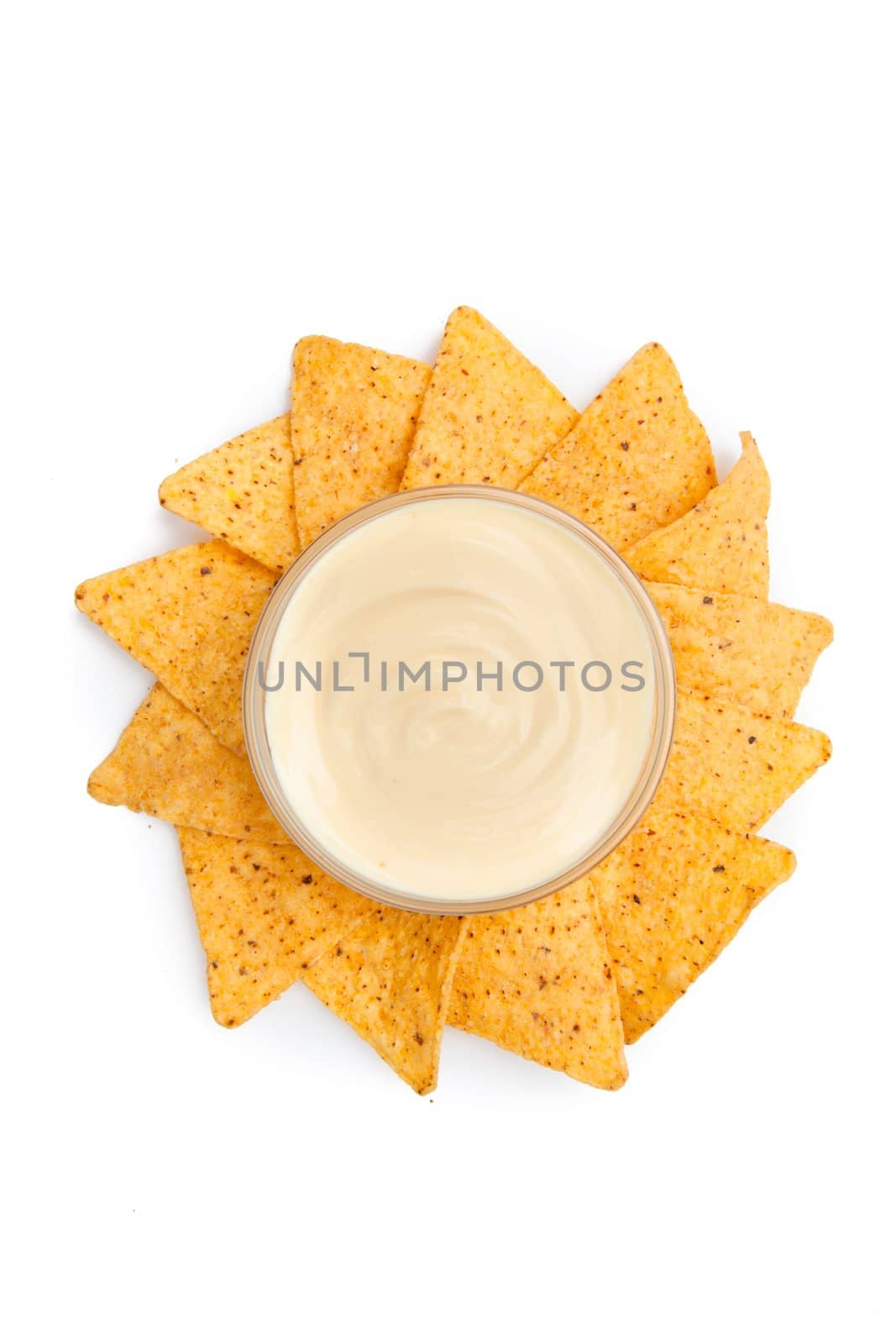 Nachos placed around a bowl of white dip against a white background