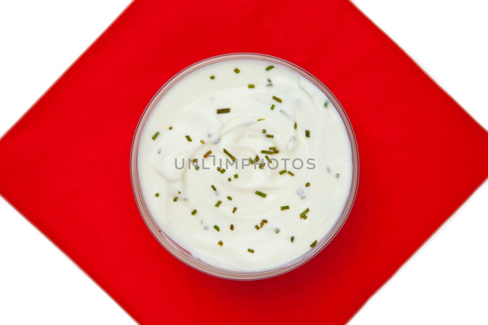 Bowl of dip with herbs on a red napkin against a white background