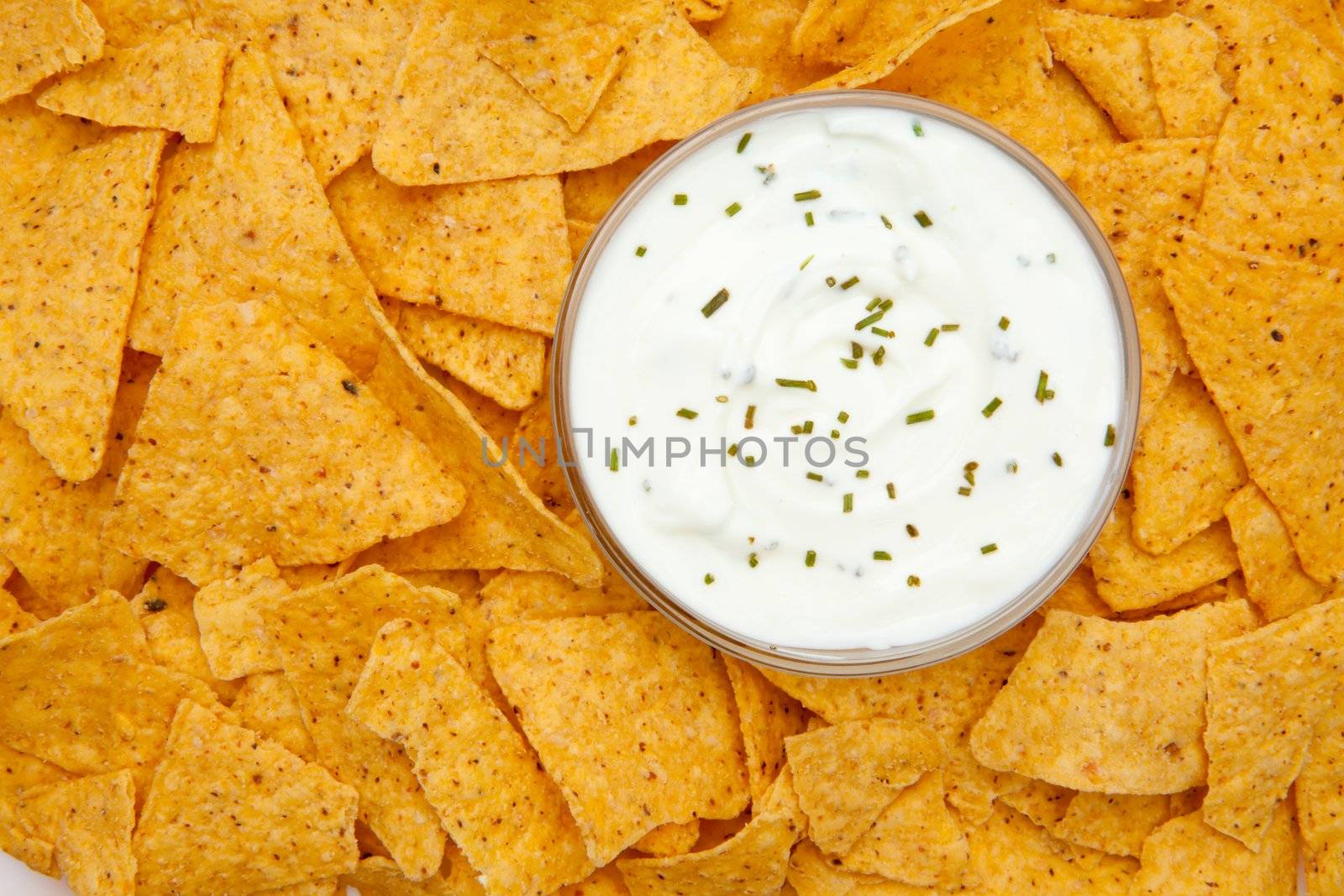 Bowl of dip with herbs surrounded by nachos by Wavebreakmedia