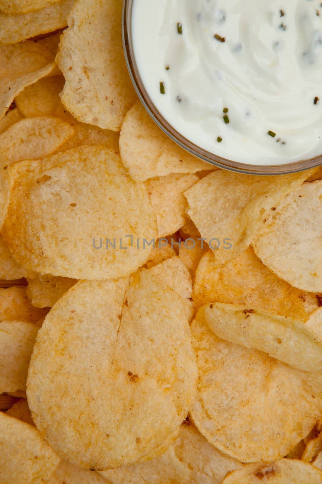 close up of a bowl of dip with herbs surrounded by chips by Wavebreakmedia