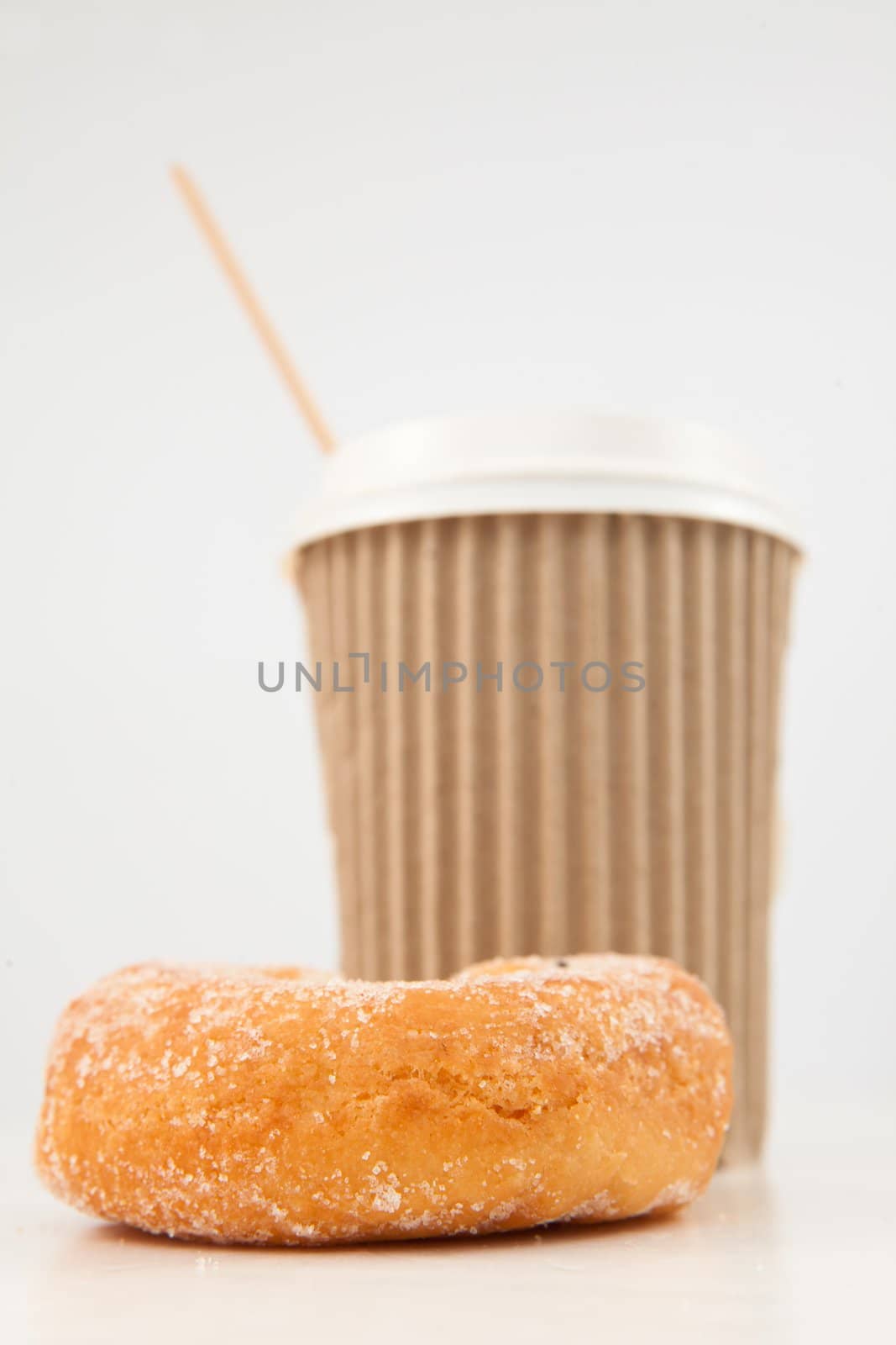 A doughnut and a cup of coffee placed side by side against a white background