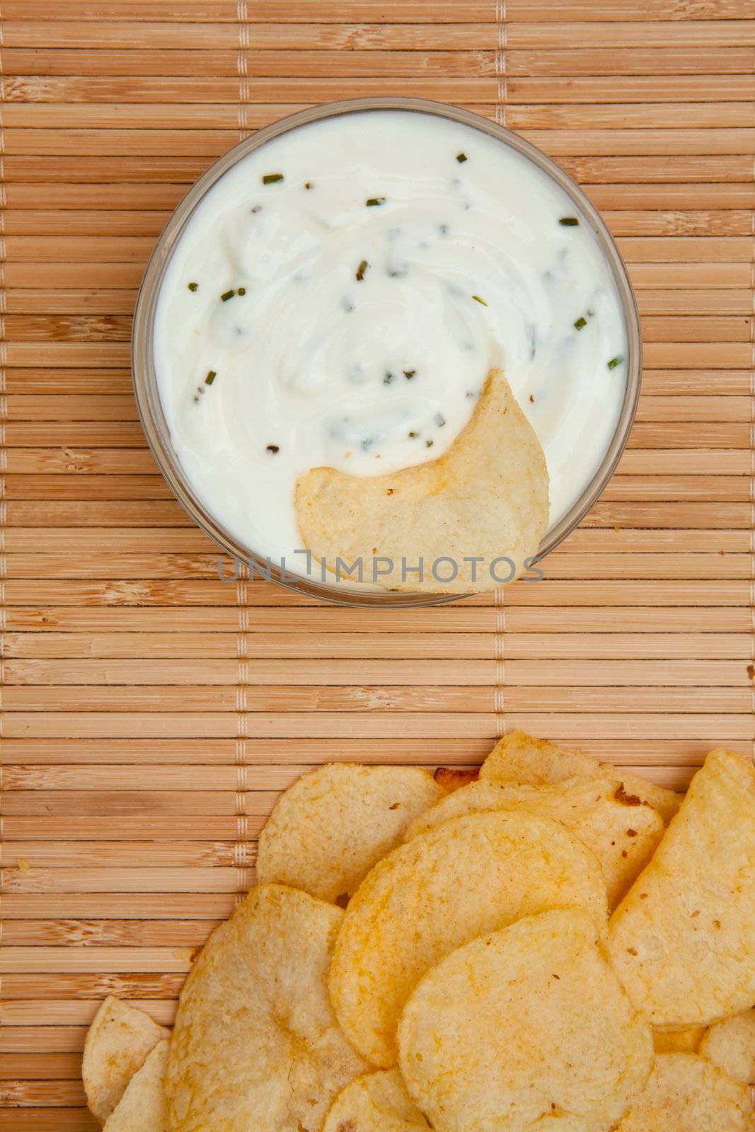 Close up of a bowl of  dip with herbs beside chips by Wavebreakmedia
