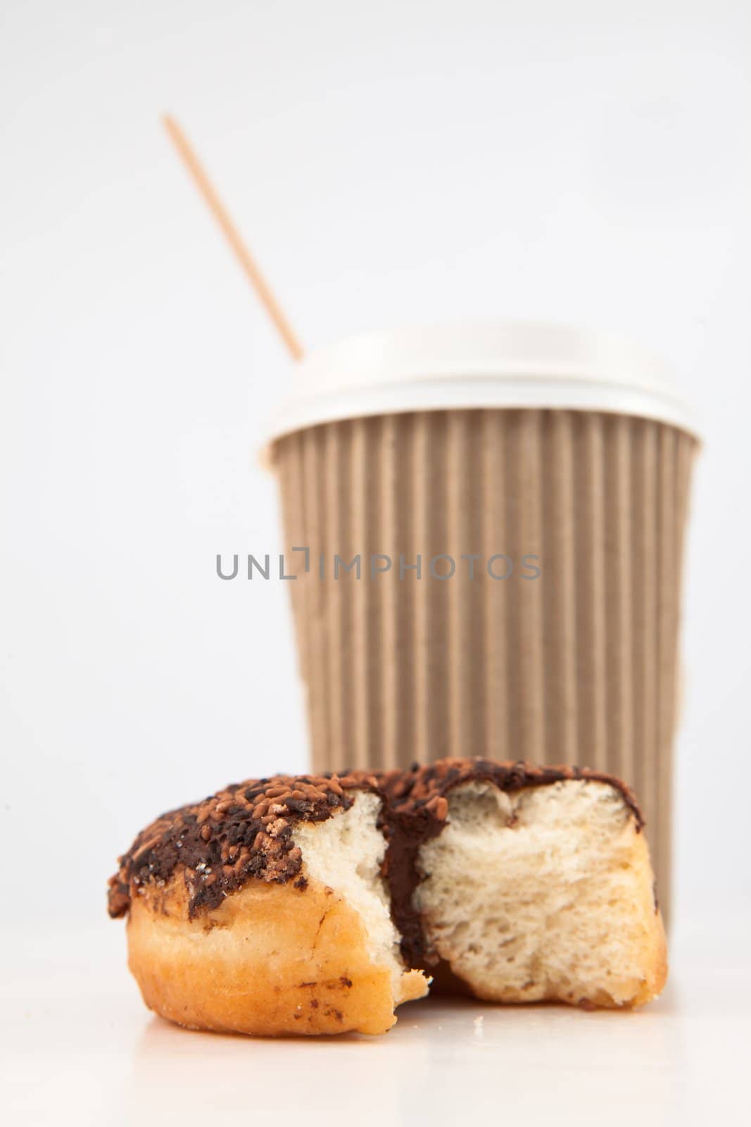 An half eaten doughnut and a cup of coffee placed together against a white background