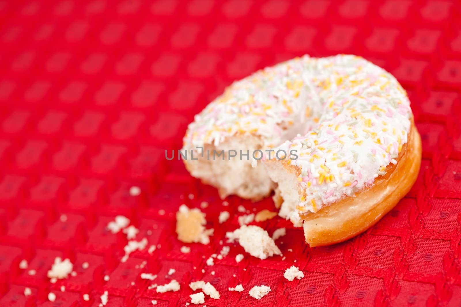 Half eaten doughnut with whipped cream on a red tablecloth
