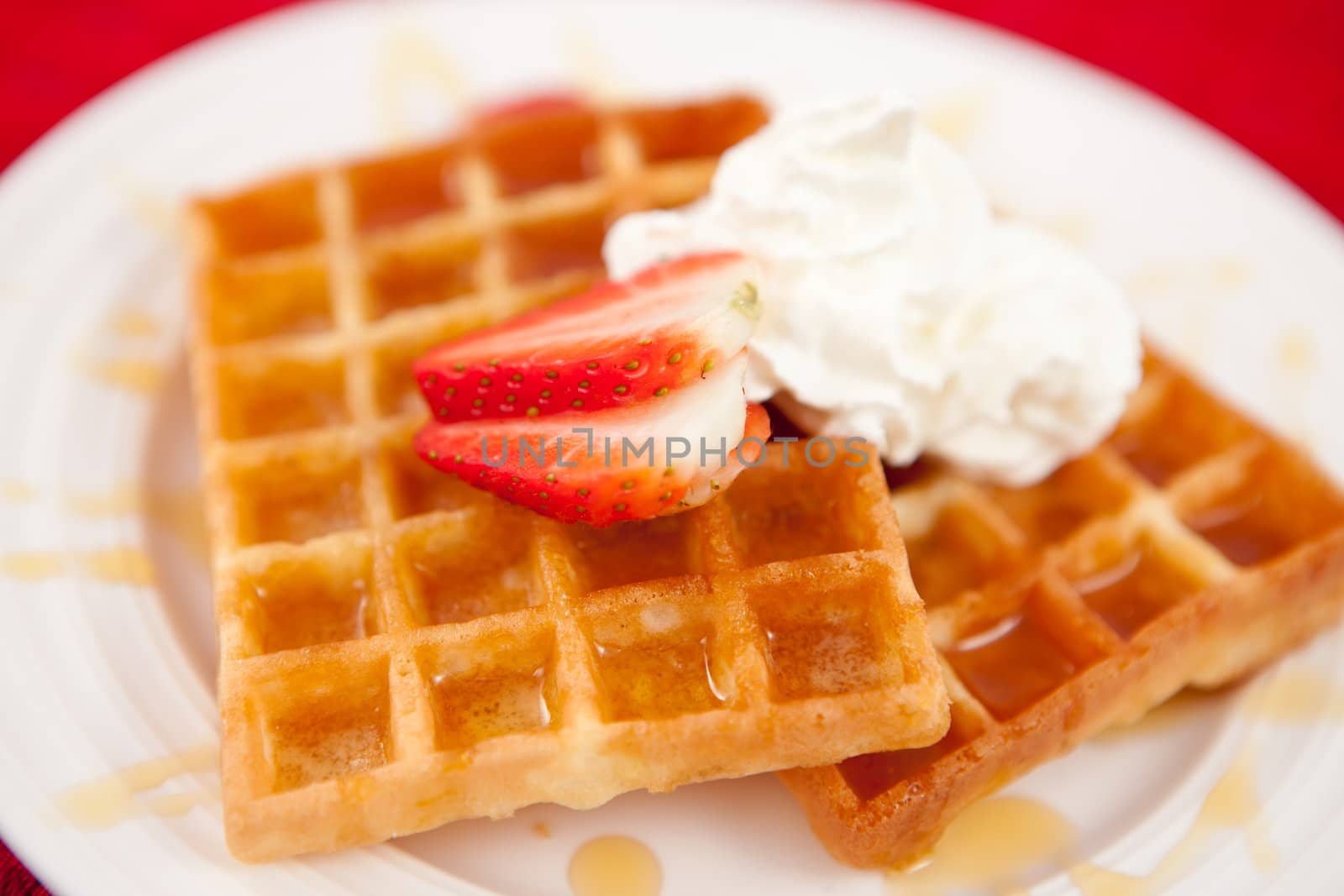 Waffles with whipped cream and strawberry and syrup by Wavebreakmedia