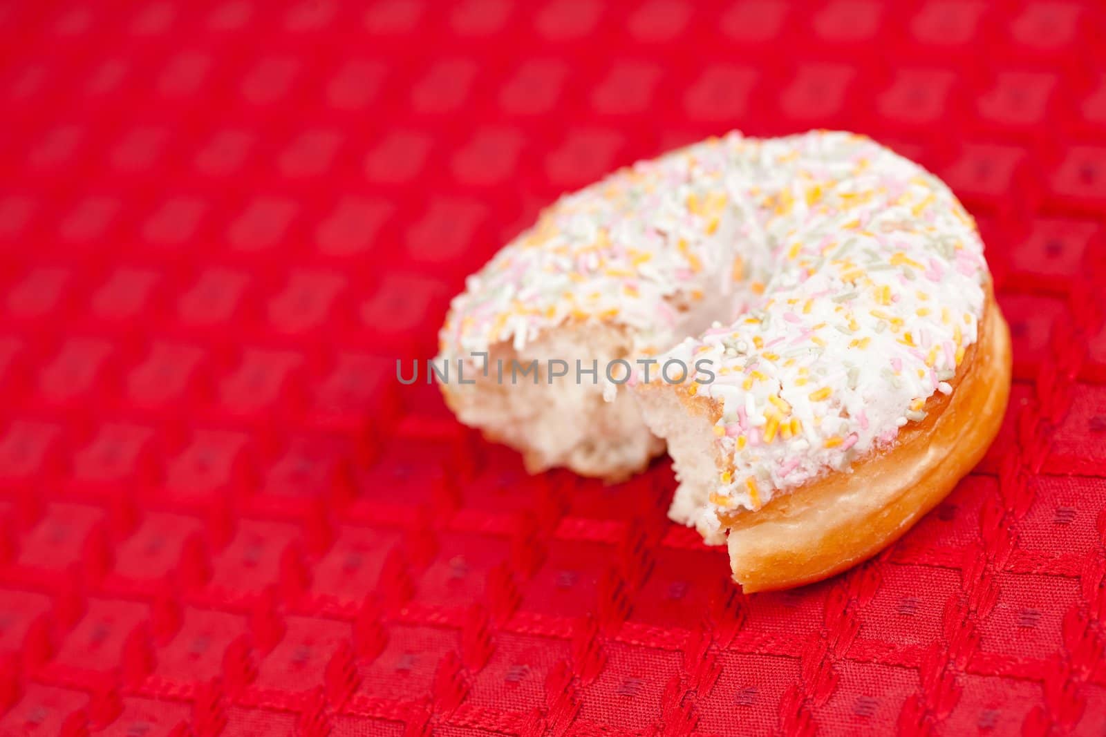 Half doughnut with whipped cream on a red tablecloth