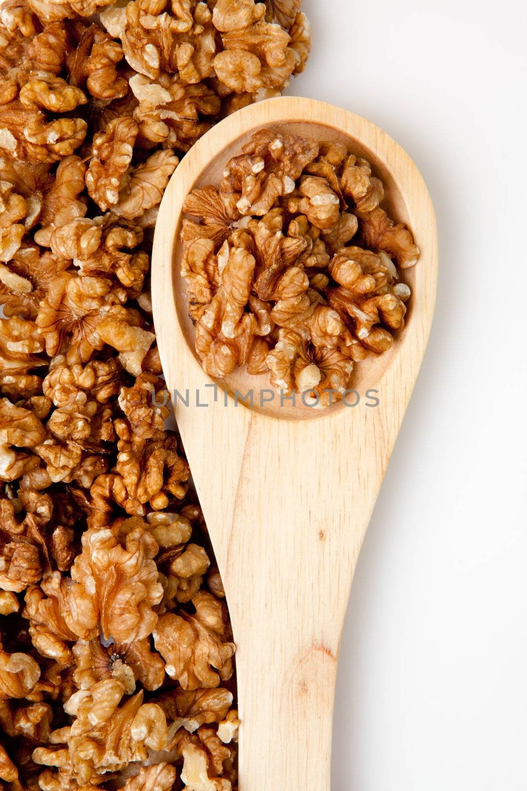 Wooden spoon with nuts against a white background