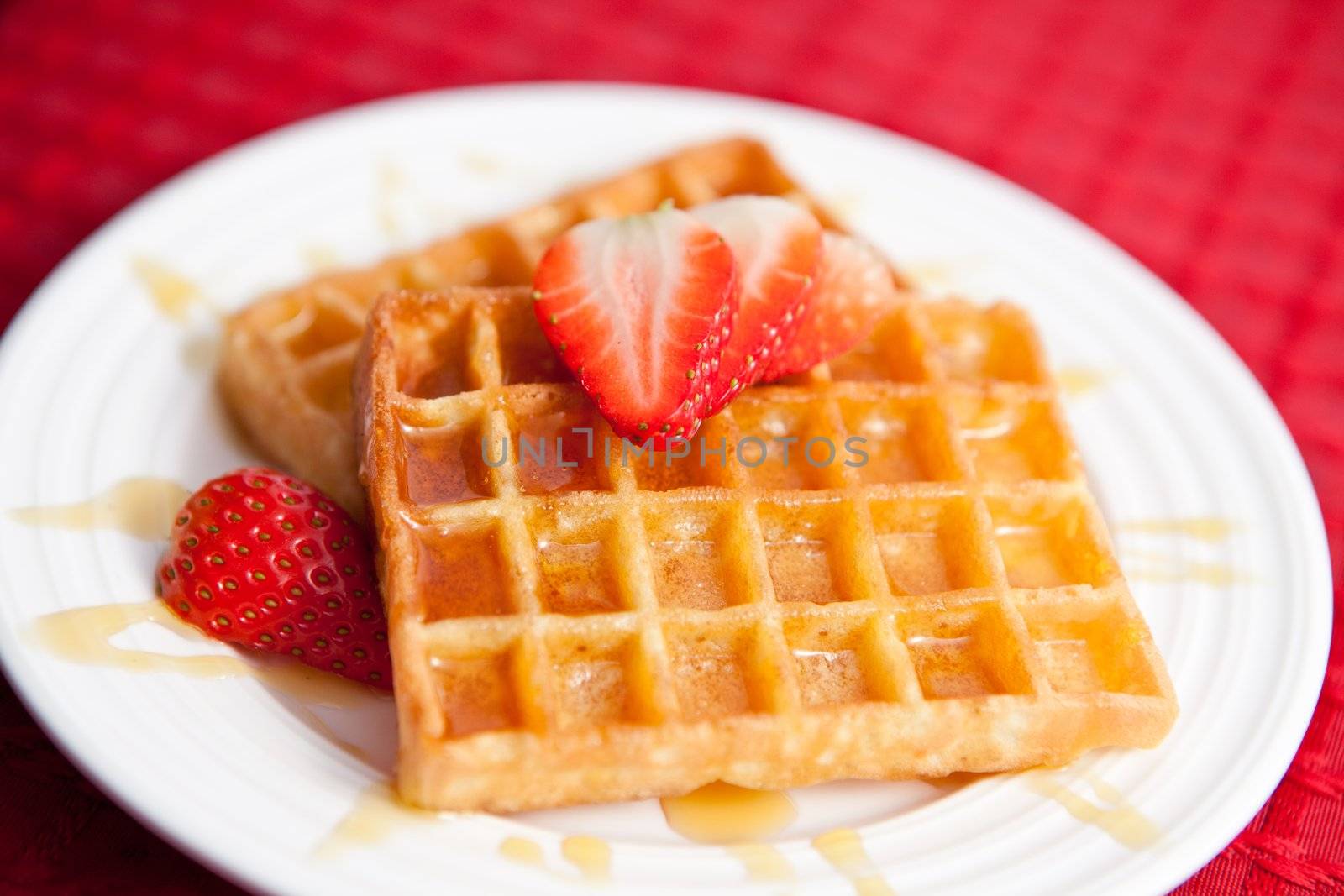 Waffles and half cut strawberry together in a white plate by Wavebreakmedia