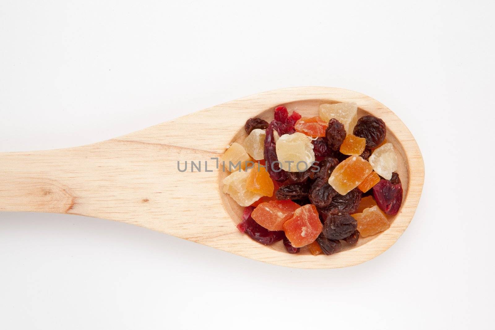 Wooden spoon with dried fruit against a white background