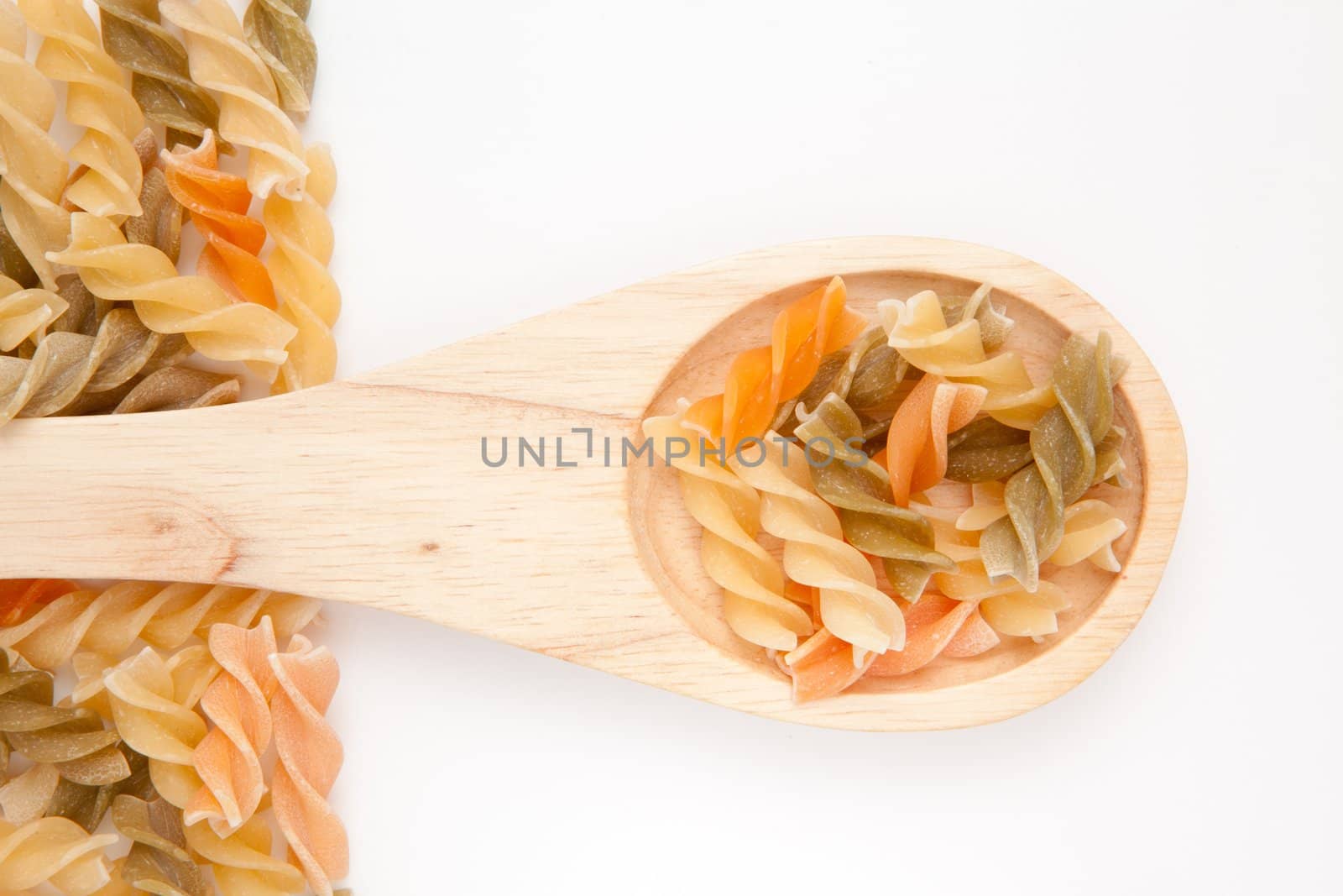 Wooden spoon with pasta  against a white background