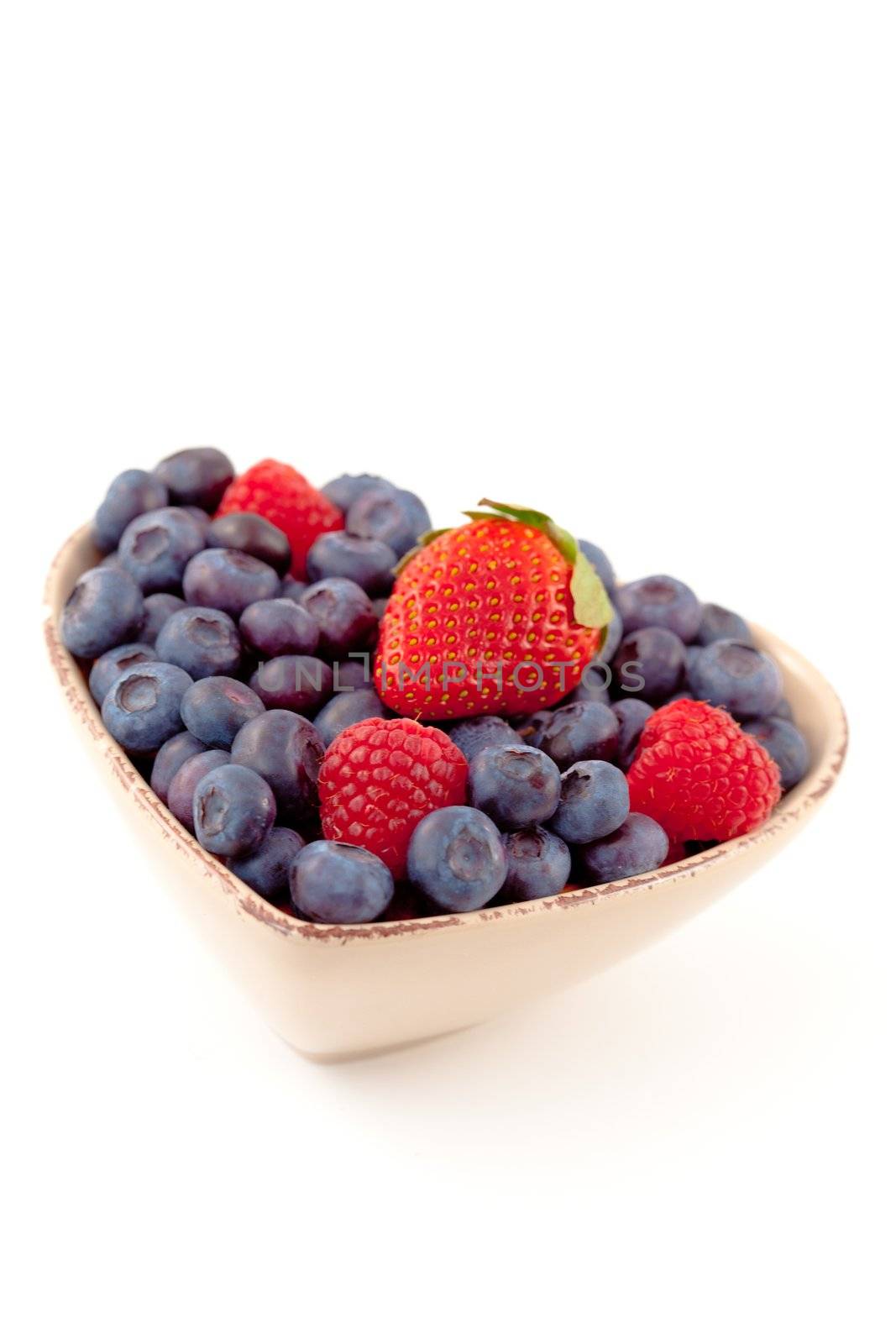 Berries in a heart shaped bowl against a white background