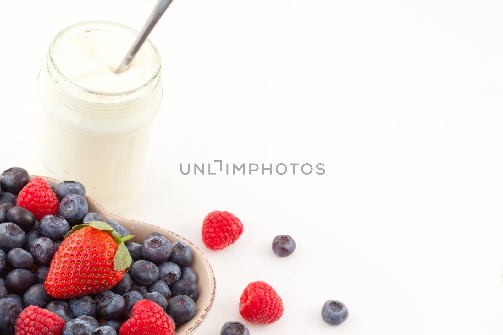 Yogurt and berries against a white background