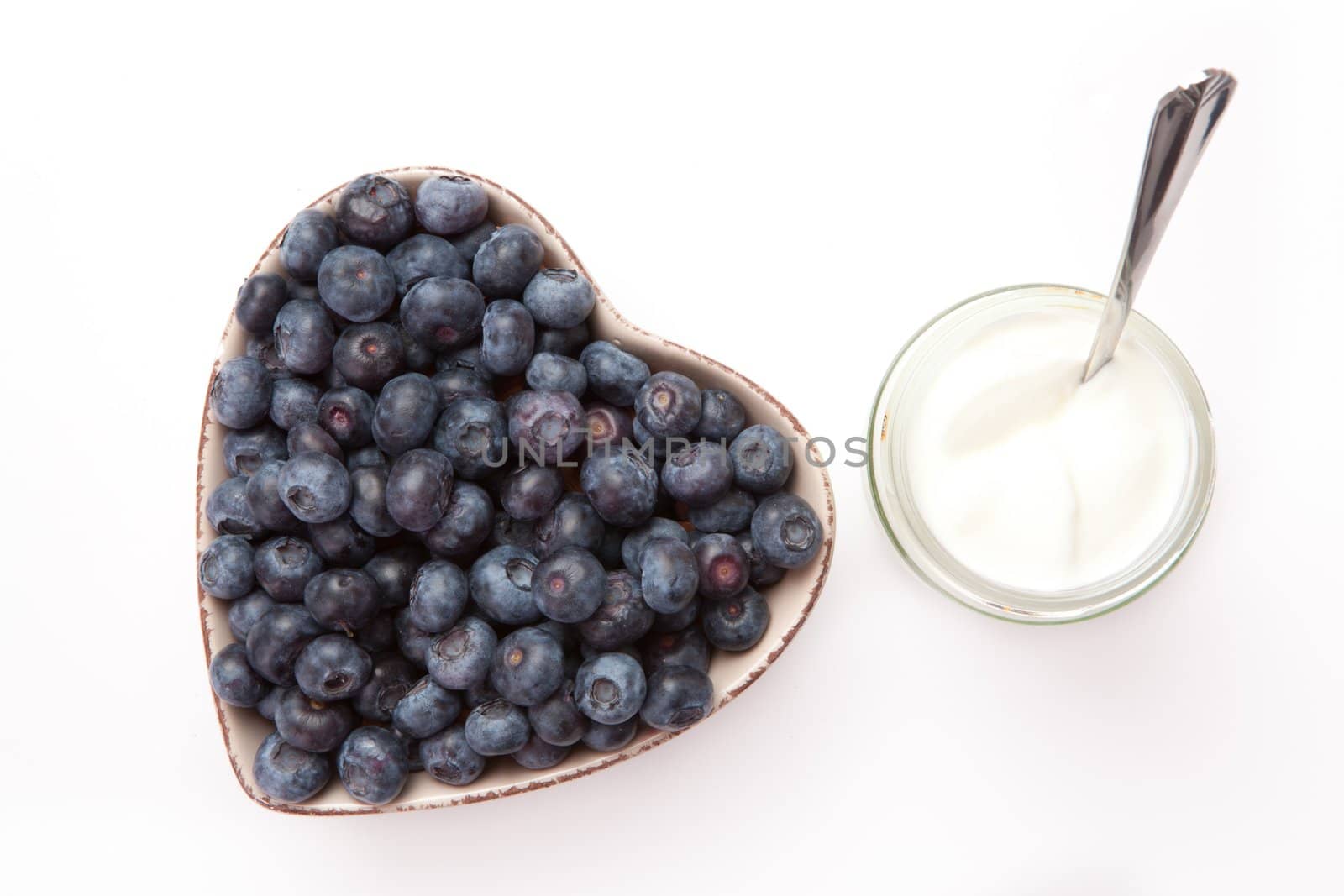 White yogurt and blueberries in a heart shaped bowl  by Wavebreakmedia