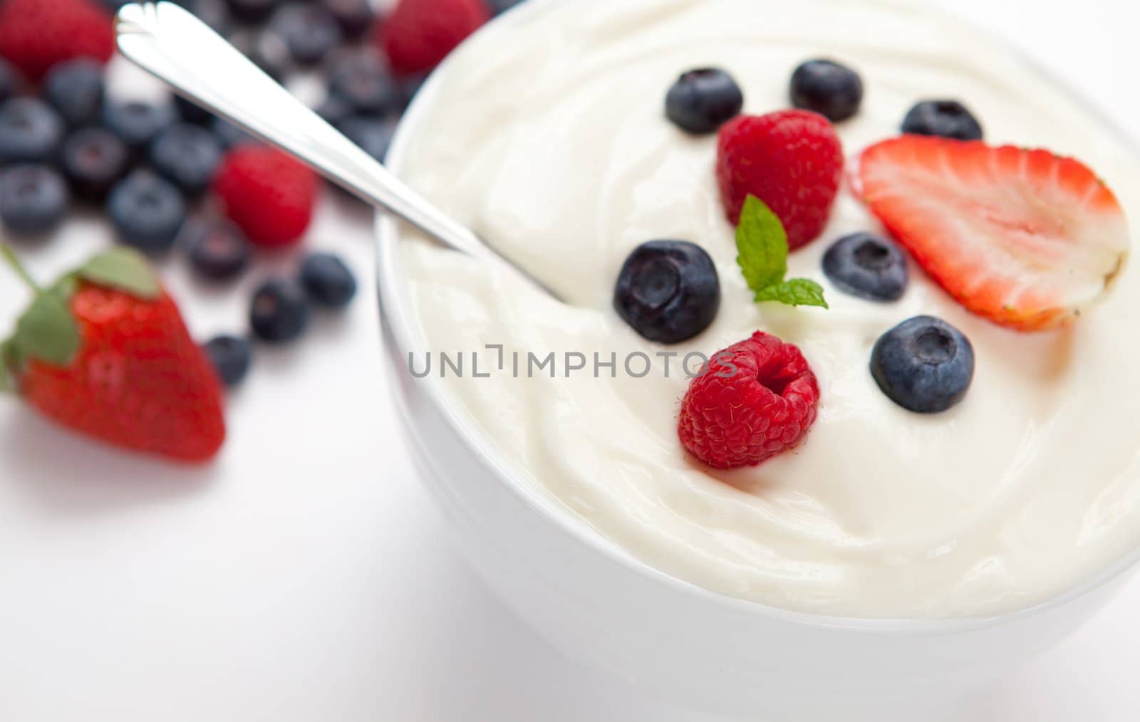 Berries in a bowl with cream  against a white background