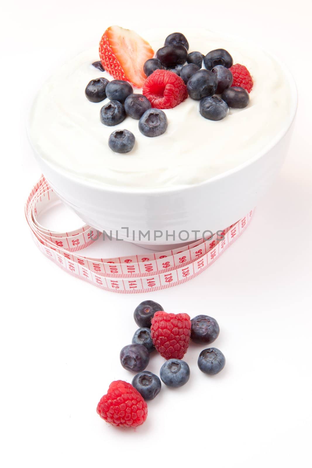 Tape measure and berries cream against a white background