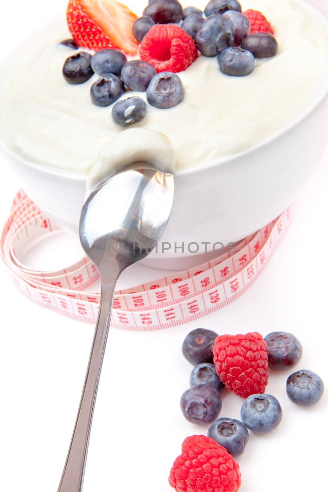 Berries cream and spoon with a tape measure  against a white background