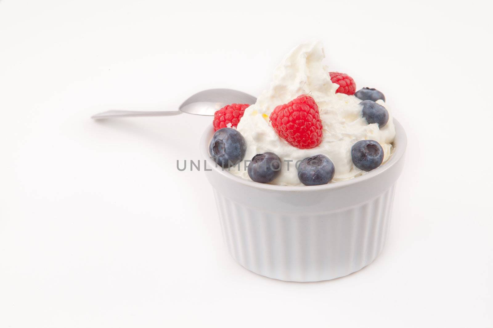 Jar of berries and whipped cream  with spoon  against white background