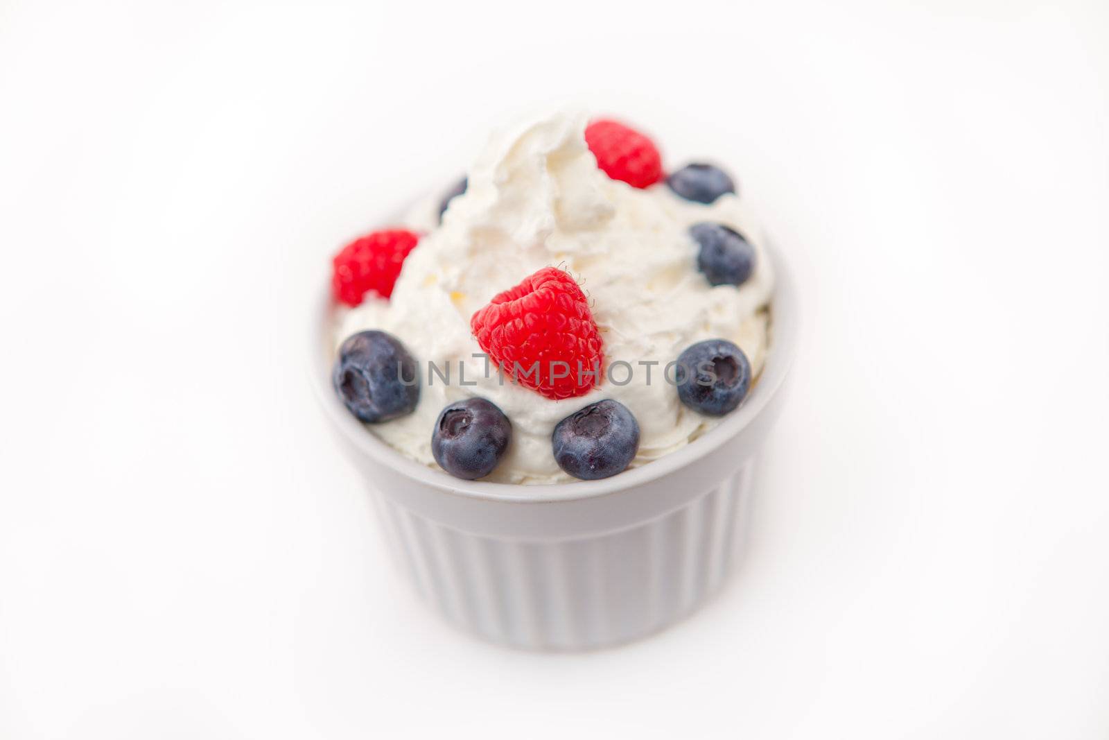 Jar of fruits and whipped cream against white background