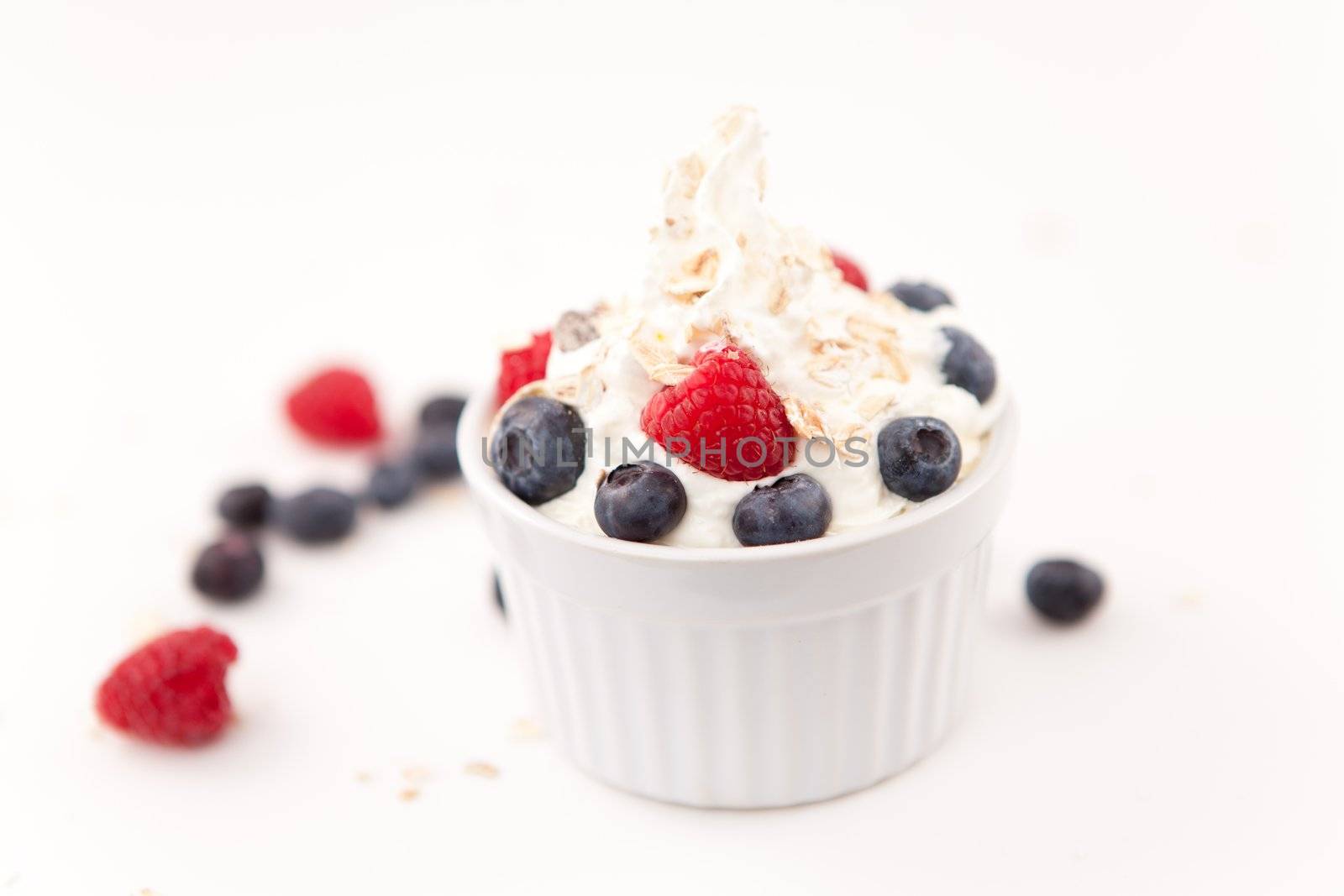 Jar of whipped cream and berries against white background