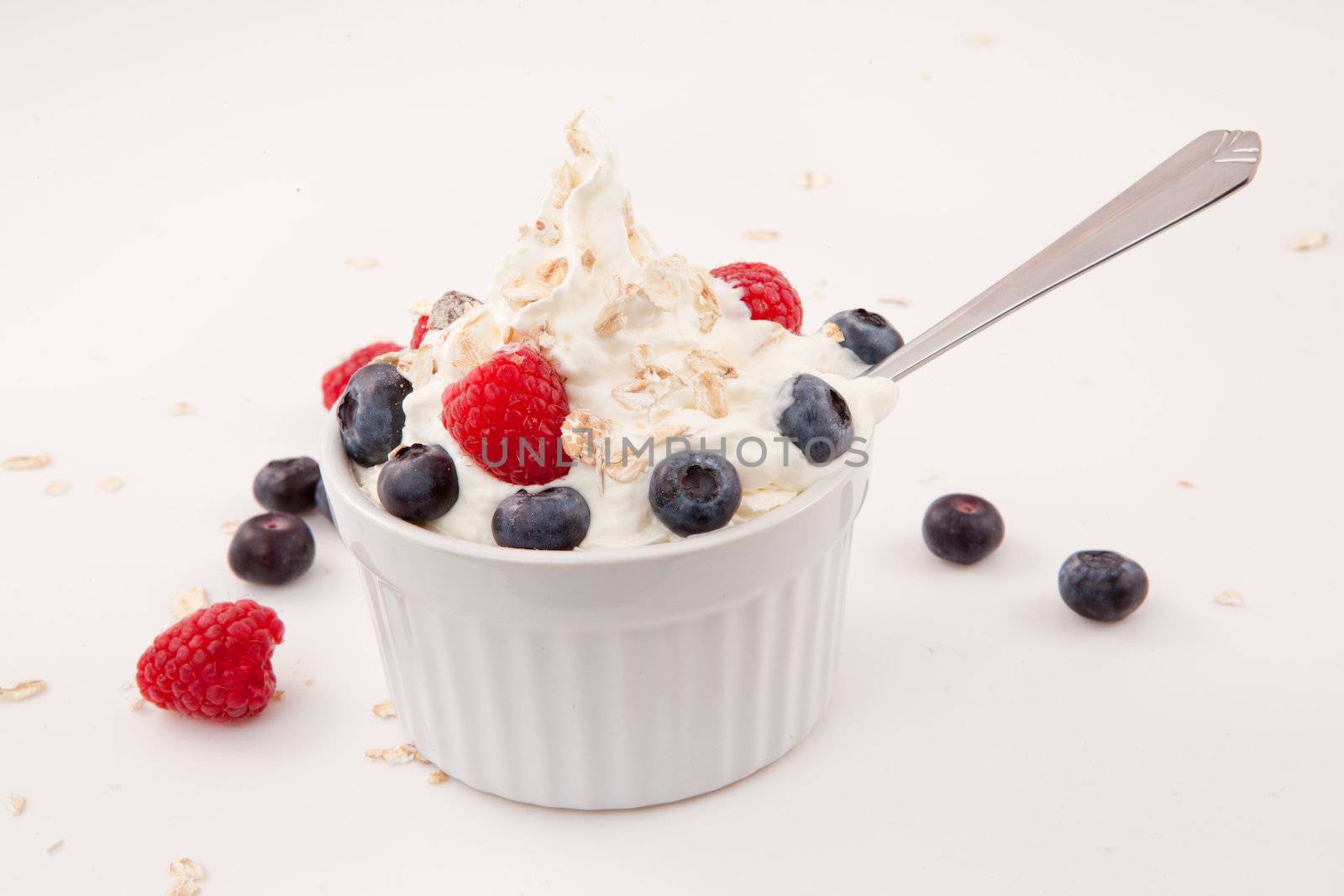 White jar of berries and whipped cream with spoon by Wavebreakmedia