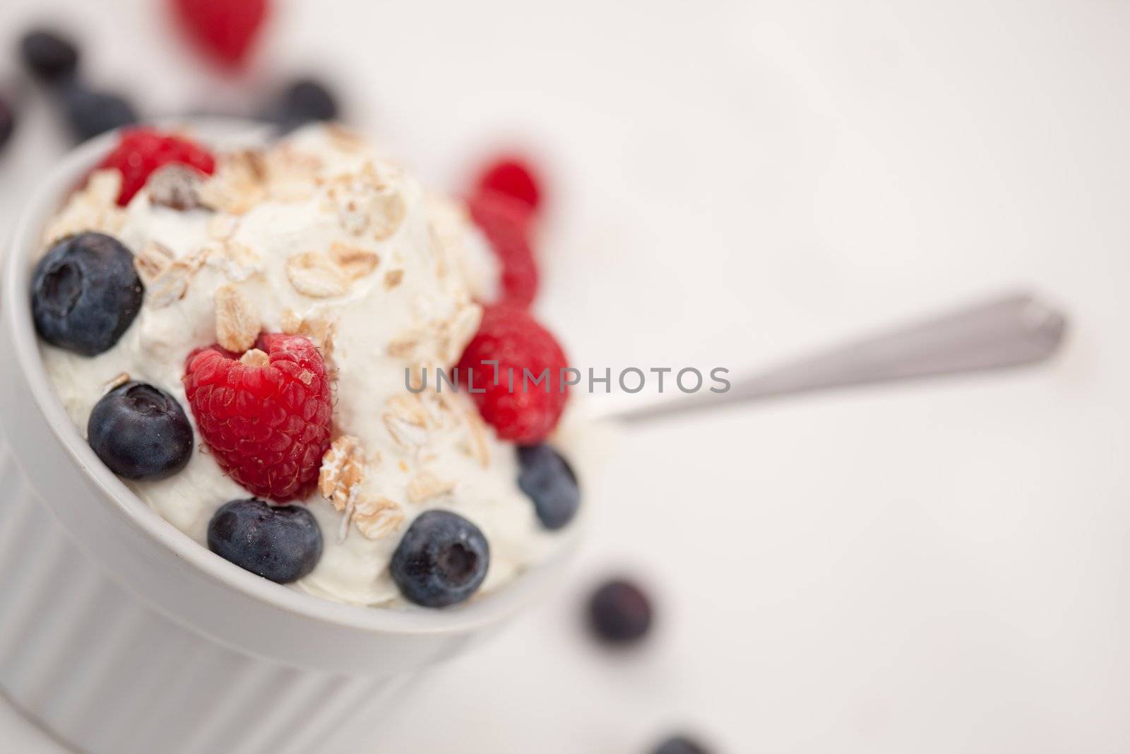 Jar of fruits and whipped cream with spoon against white background