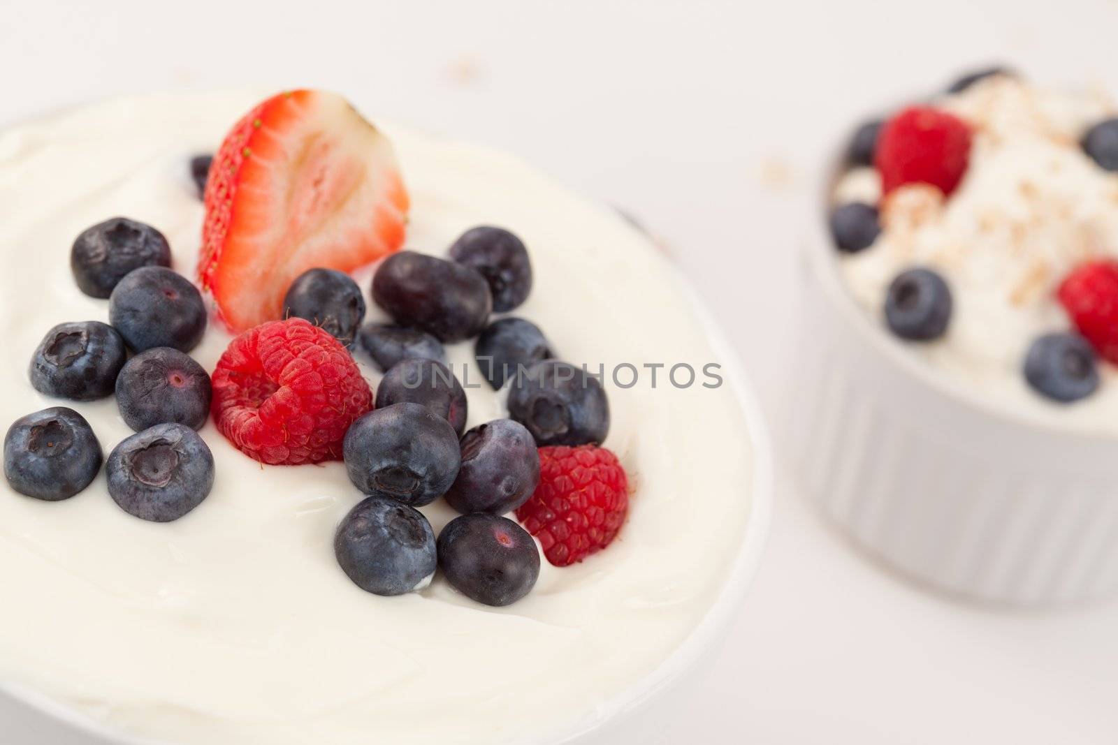 Bowl of cream with different berries against a white background