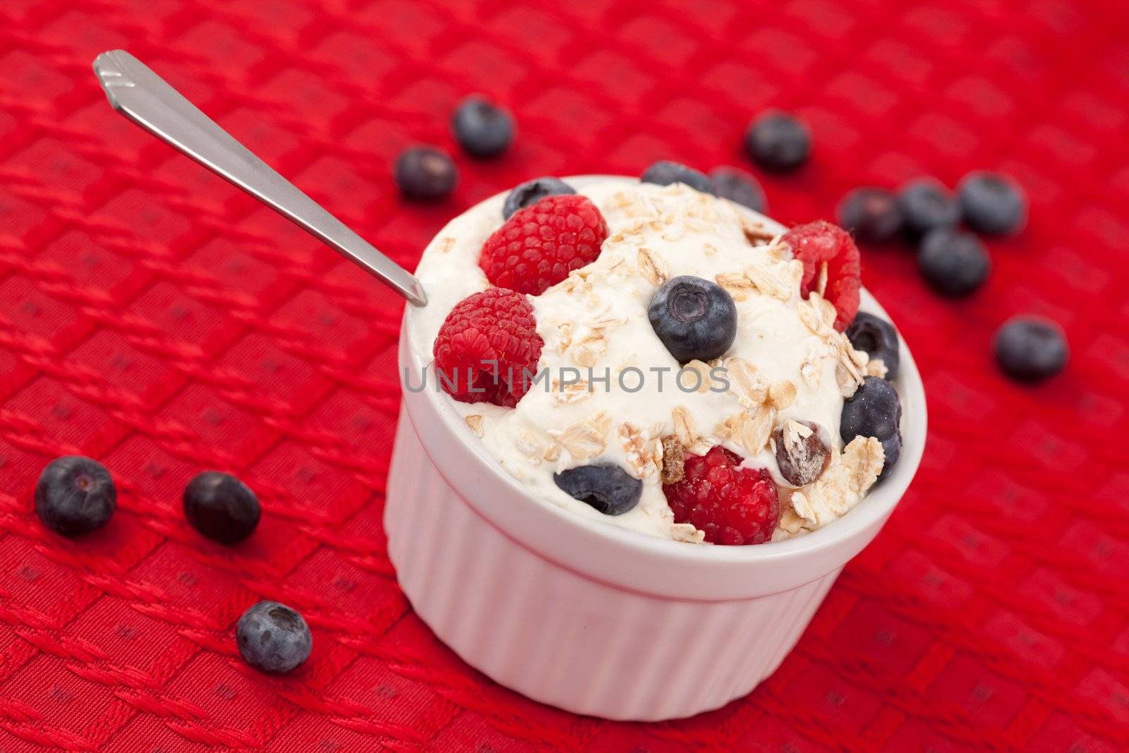 Pot of berries and whipped cream with spoon on the red carpet